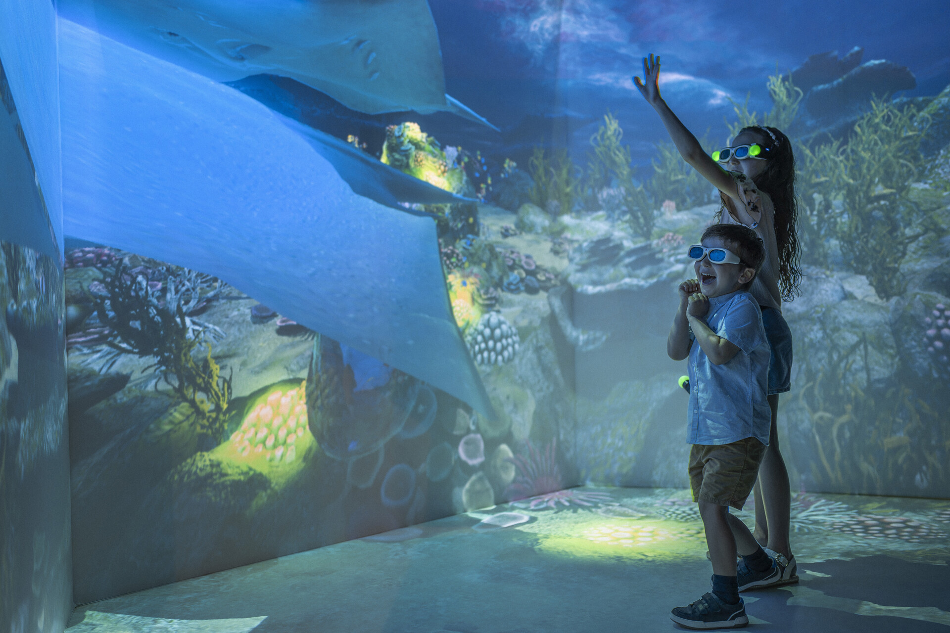 Two children excitably looking at marine life in a hologram room