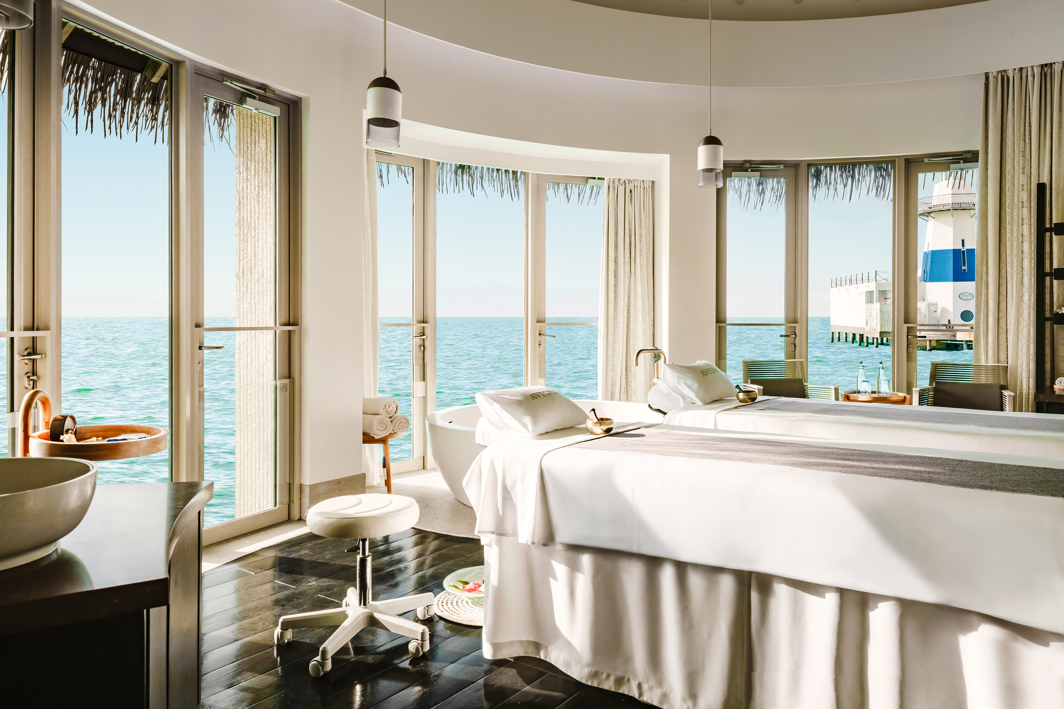 Luxurious spa room at InterContinental Maldives with ocean view, massage tables, and serene ambiance.