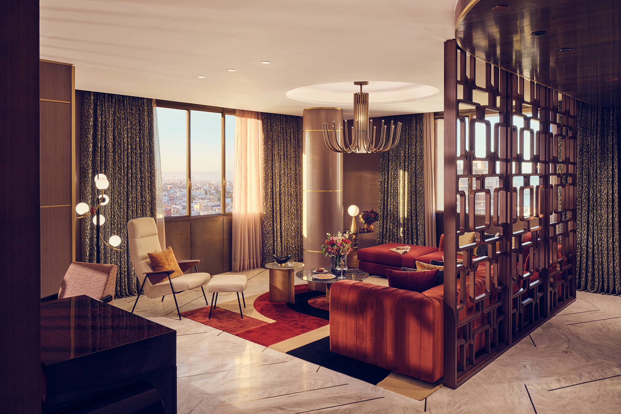 The lounge of a apartment suite at Royal Mansour Casablanca with sweeping views featuring plush furniture, gold decor and an ornate room divider