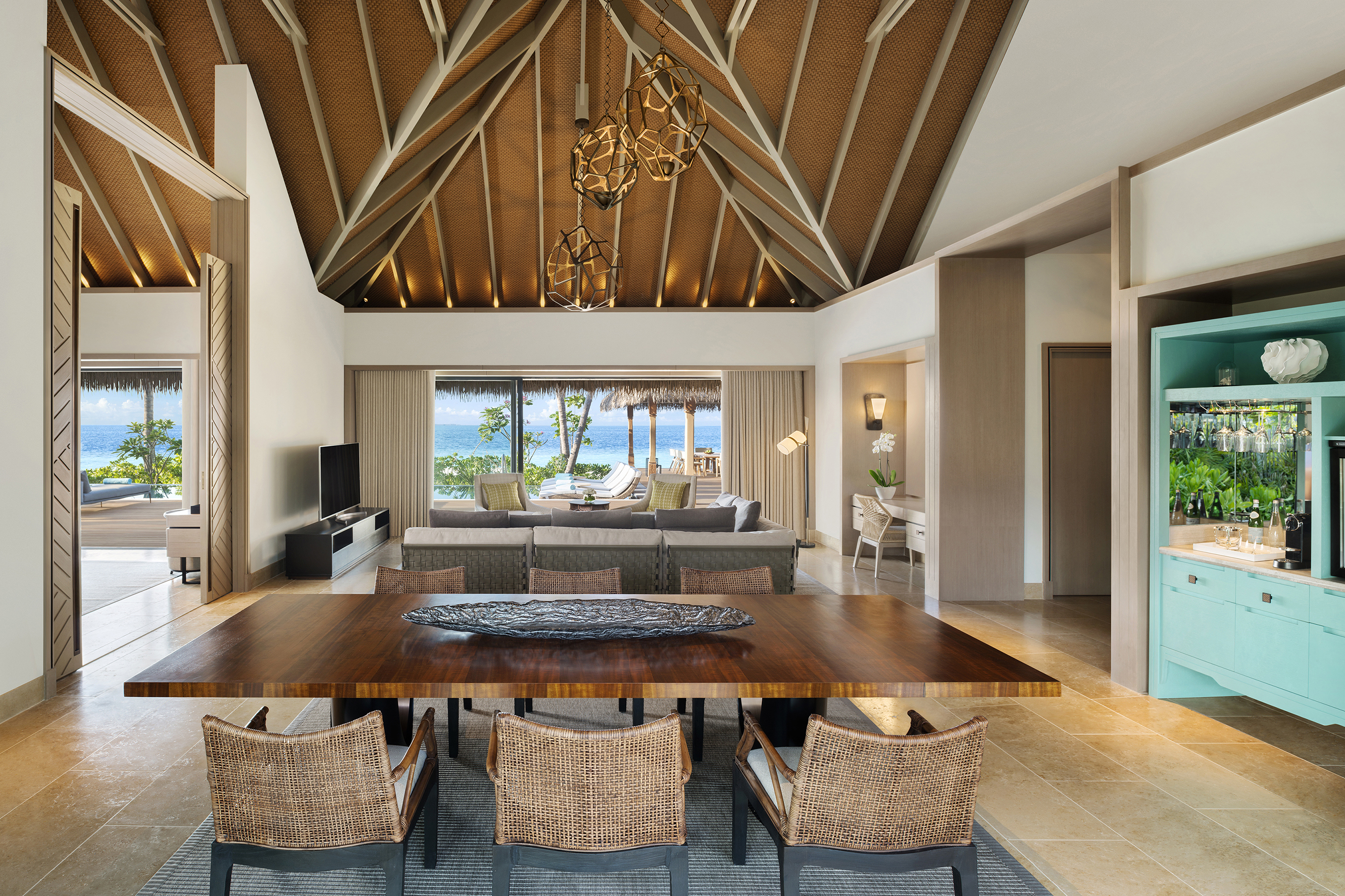 Living and dining area of Two Bedroom Grand Beach Villa with wooden dining table, blue cabinet and sculptural light shade details