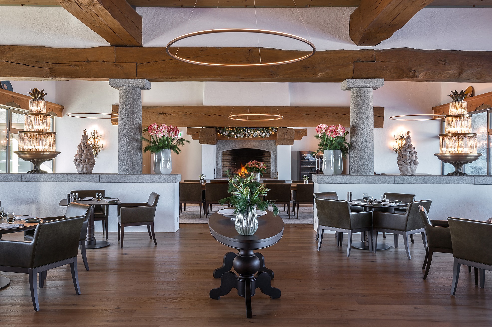 Oak Grill restaurant at Bürgenstock Hotel featuring leather chairs and tables surrounded a central side table beneath wooden beams and other decorative features in the background