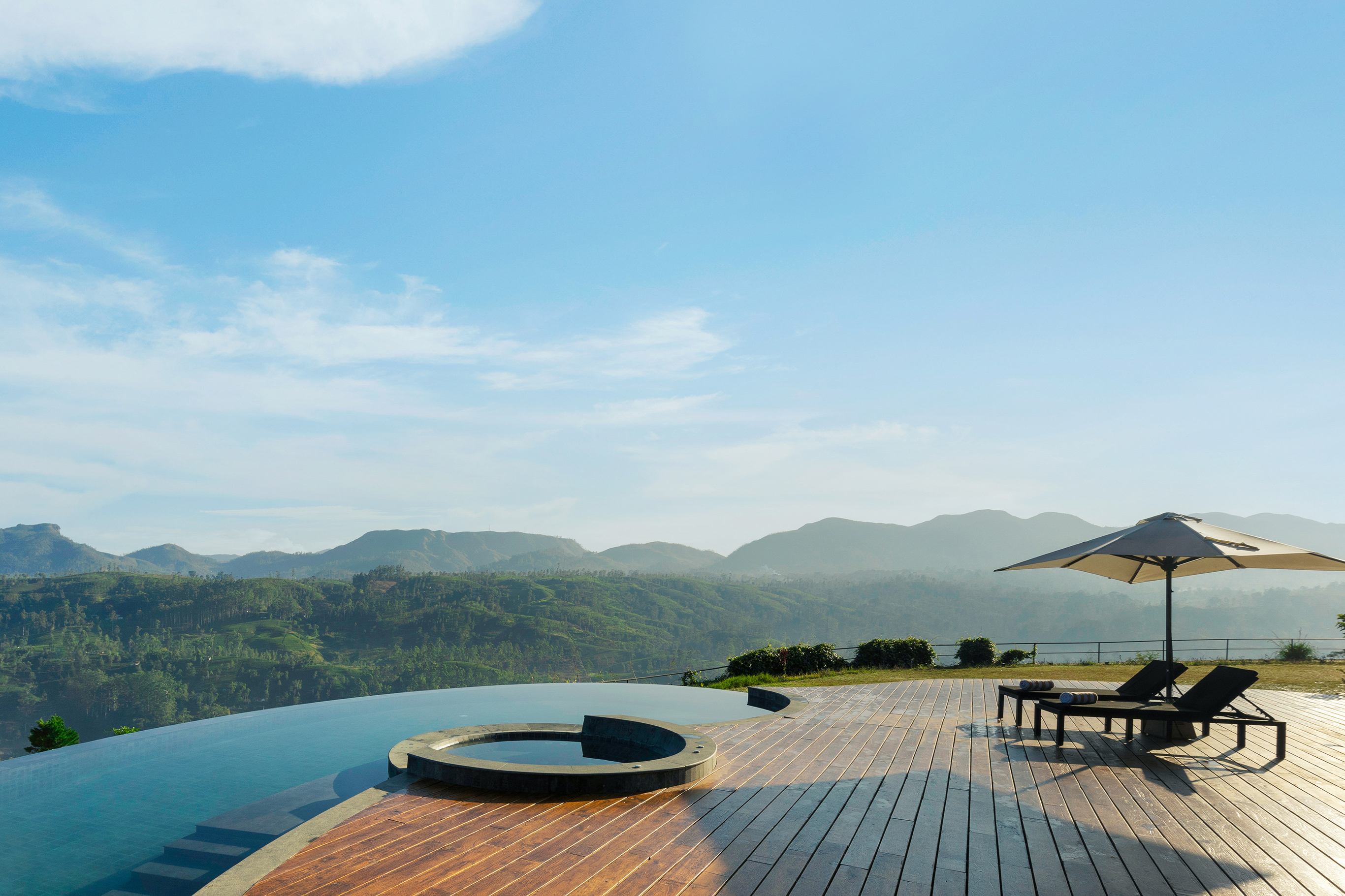 The infinity pool and jacuzzi at Uga Halloowella with a sweeping view of the landscape and sun loungers set on the wooden deck