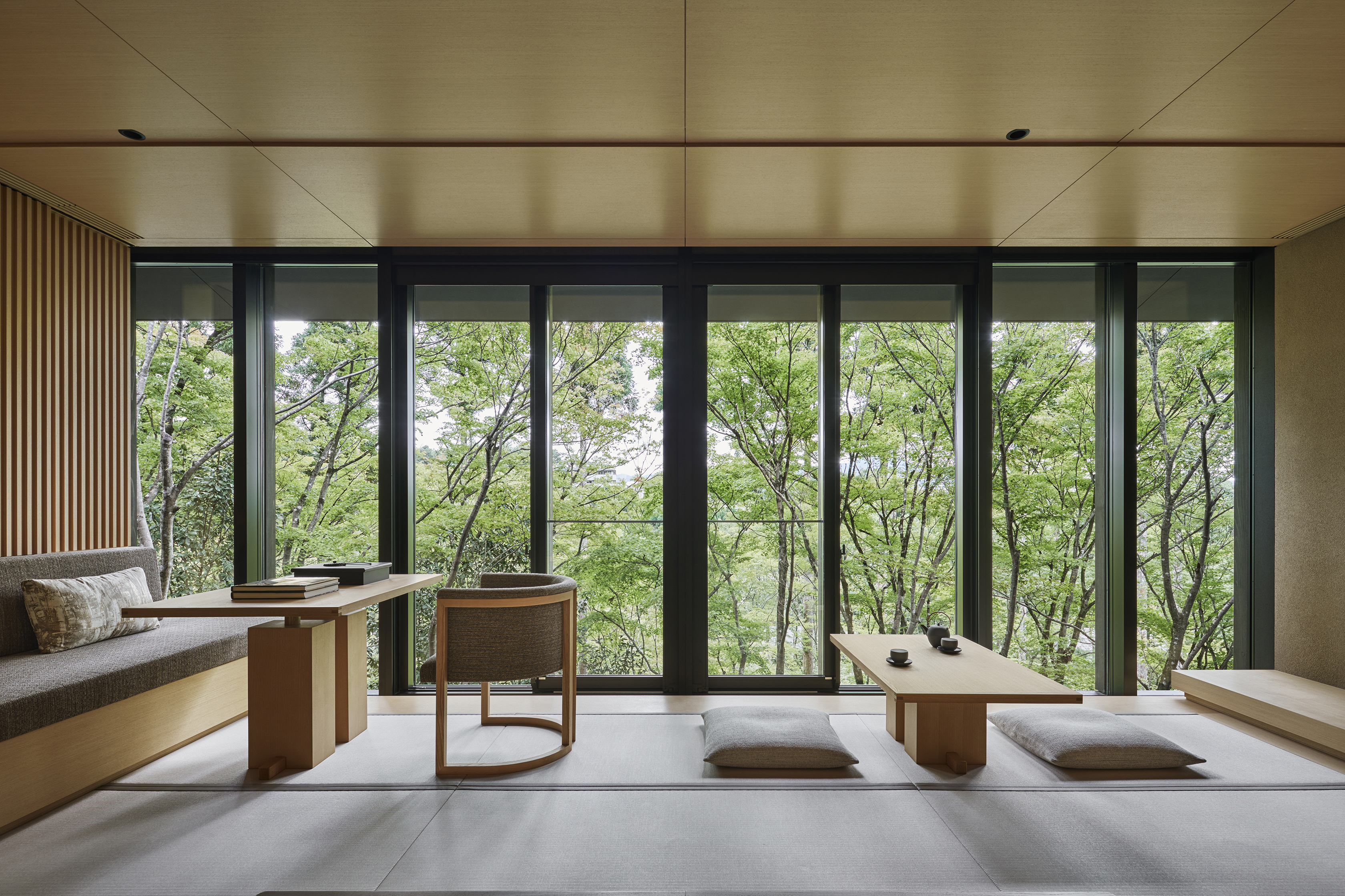 A suite with sleek pale furniture and large windows that look out to the trees