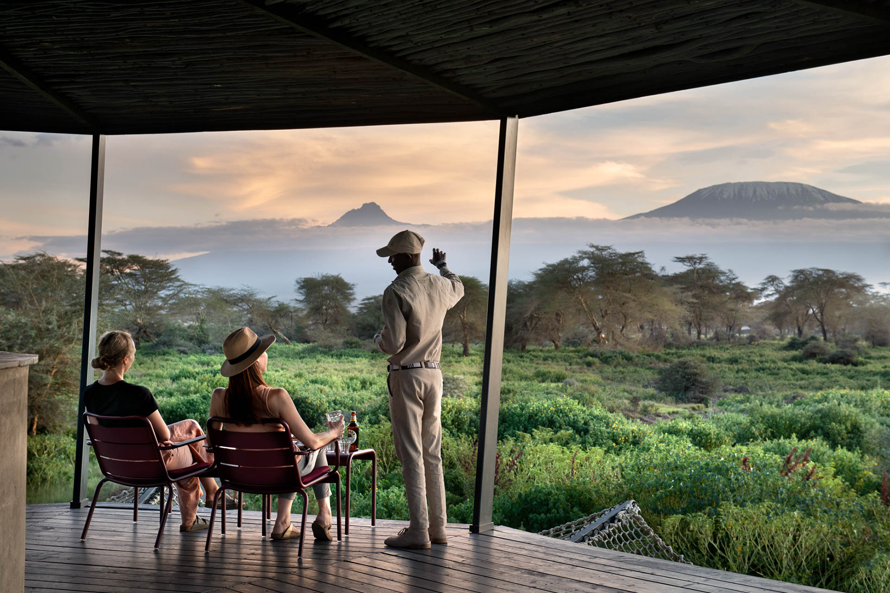 Africa, Kenya, Angama Amboseli, two women sat outside on a terrace with a guide explaining the view