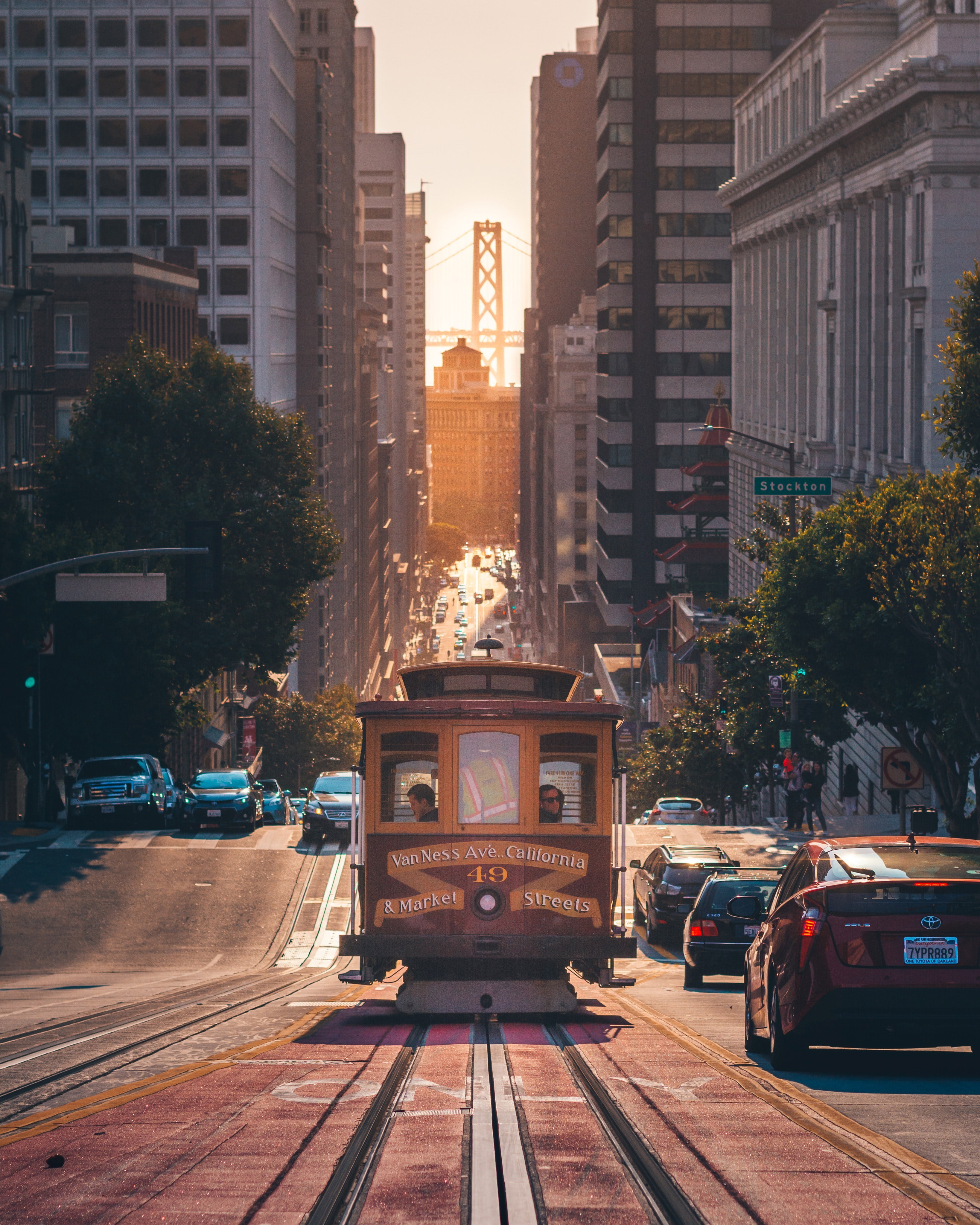 A streetcar with passengers travelling down a steep hill in San Francisco beside cars