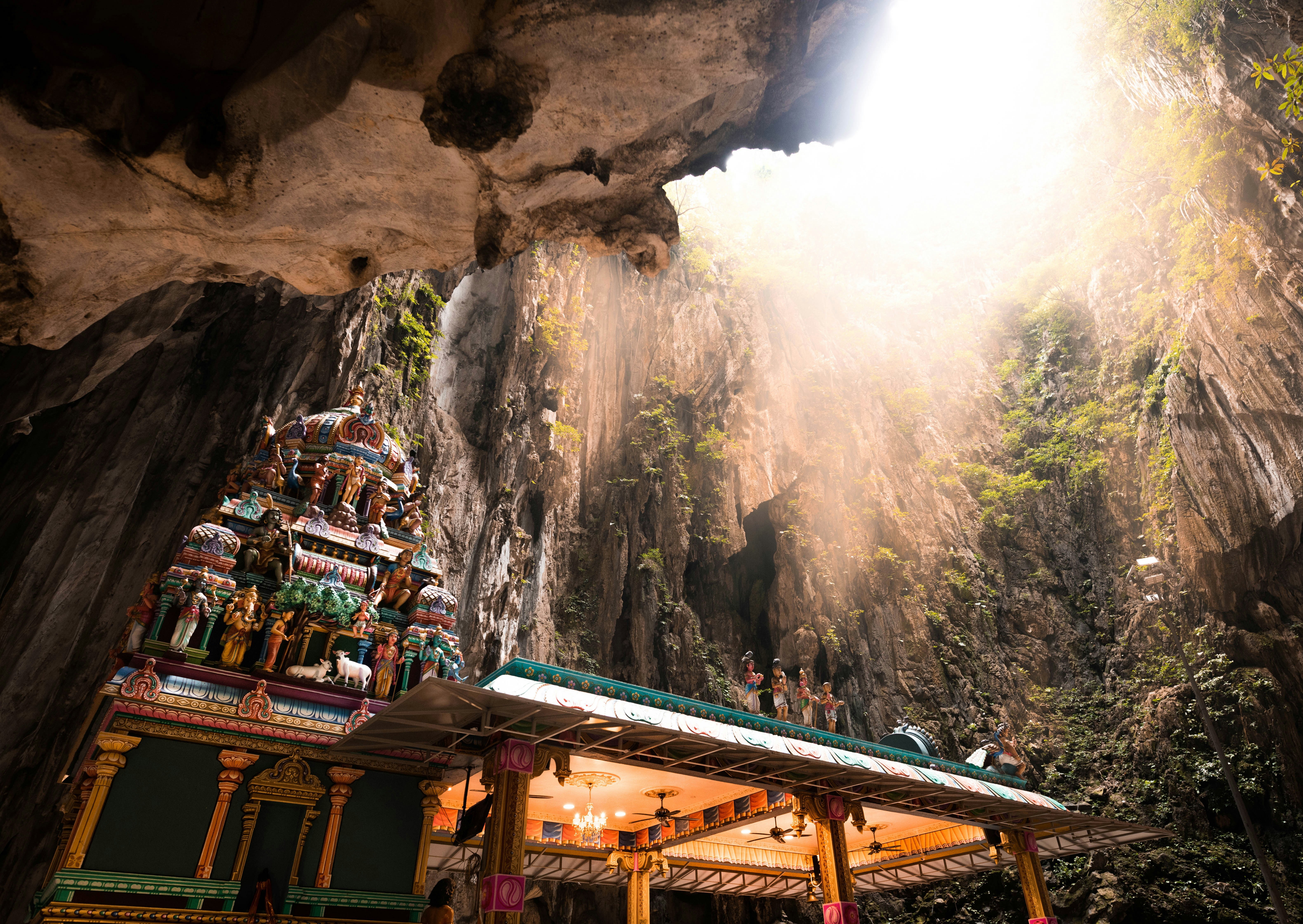 The roof of the temple in the Batu Cave with the towering cave wall ascending behind to a wide opening