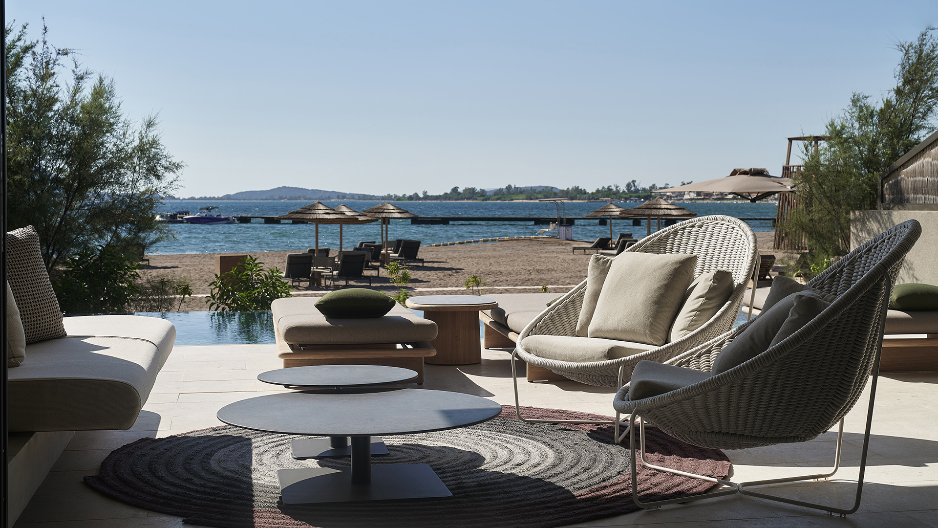 Lounge chairs and coffee table on pool terrace overlooking the beach at W Costa Navarino