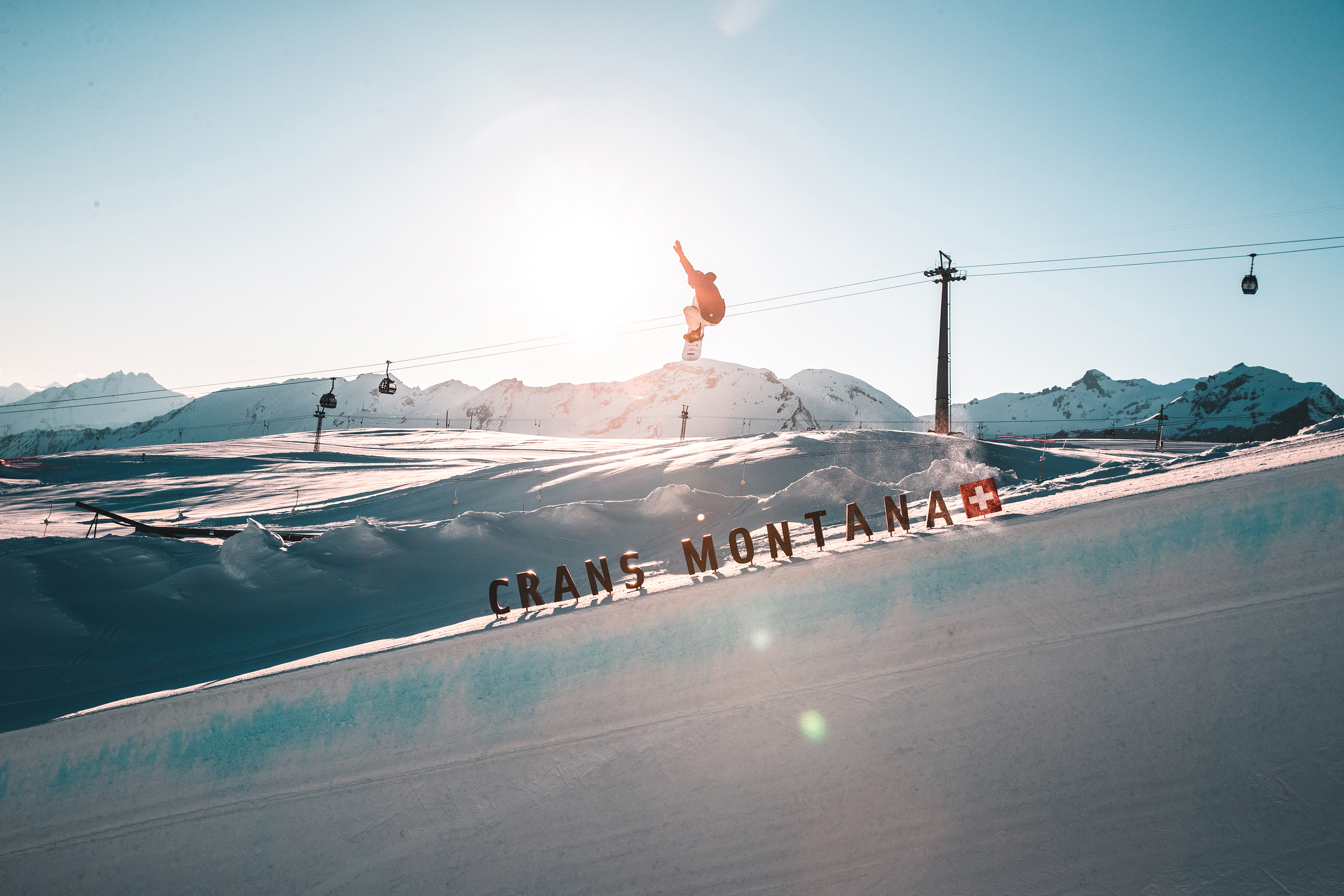 Snowboarder on the slopes of Crans Montana with a ski lift in the background