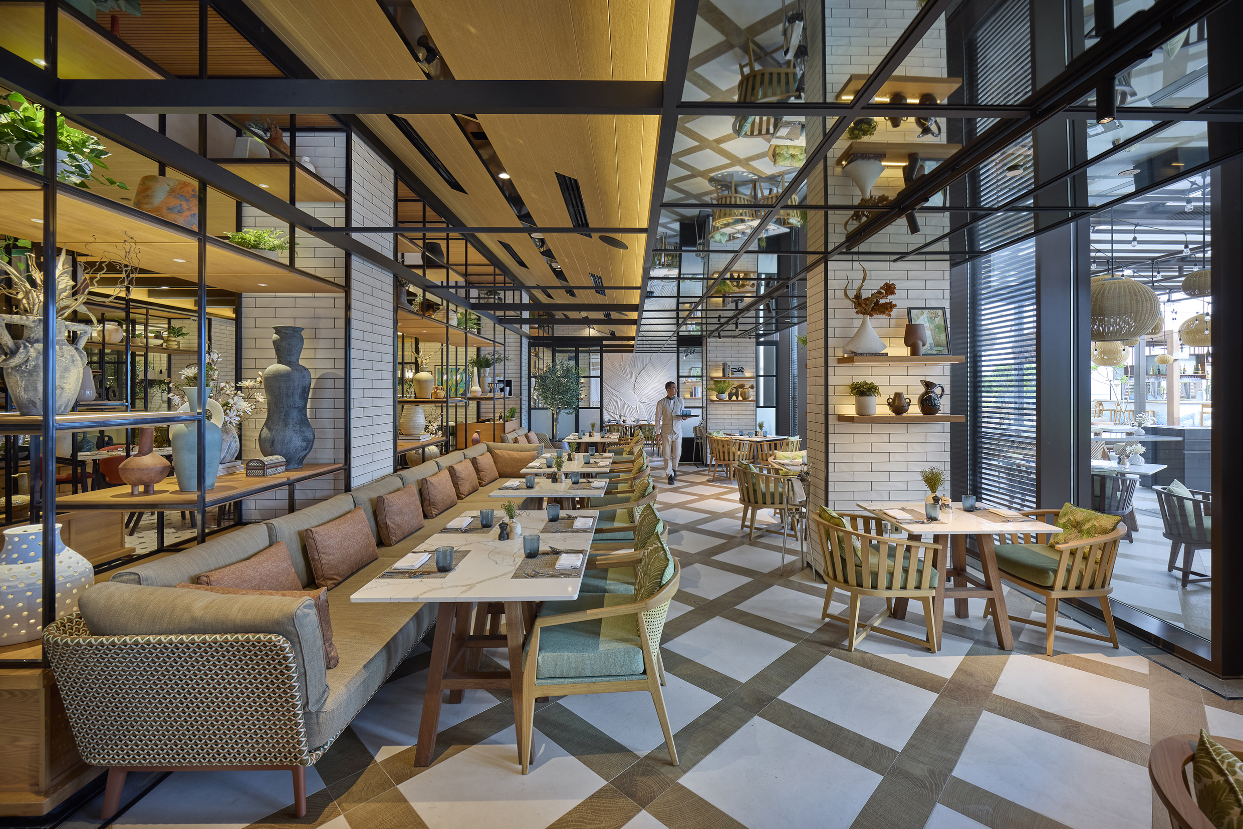 Rawya Restaurant at Mandarin Oriental Muscat featuring chic dining furniture and eclectic decor with a waiter walking around