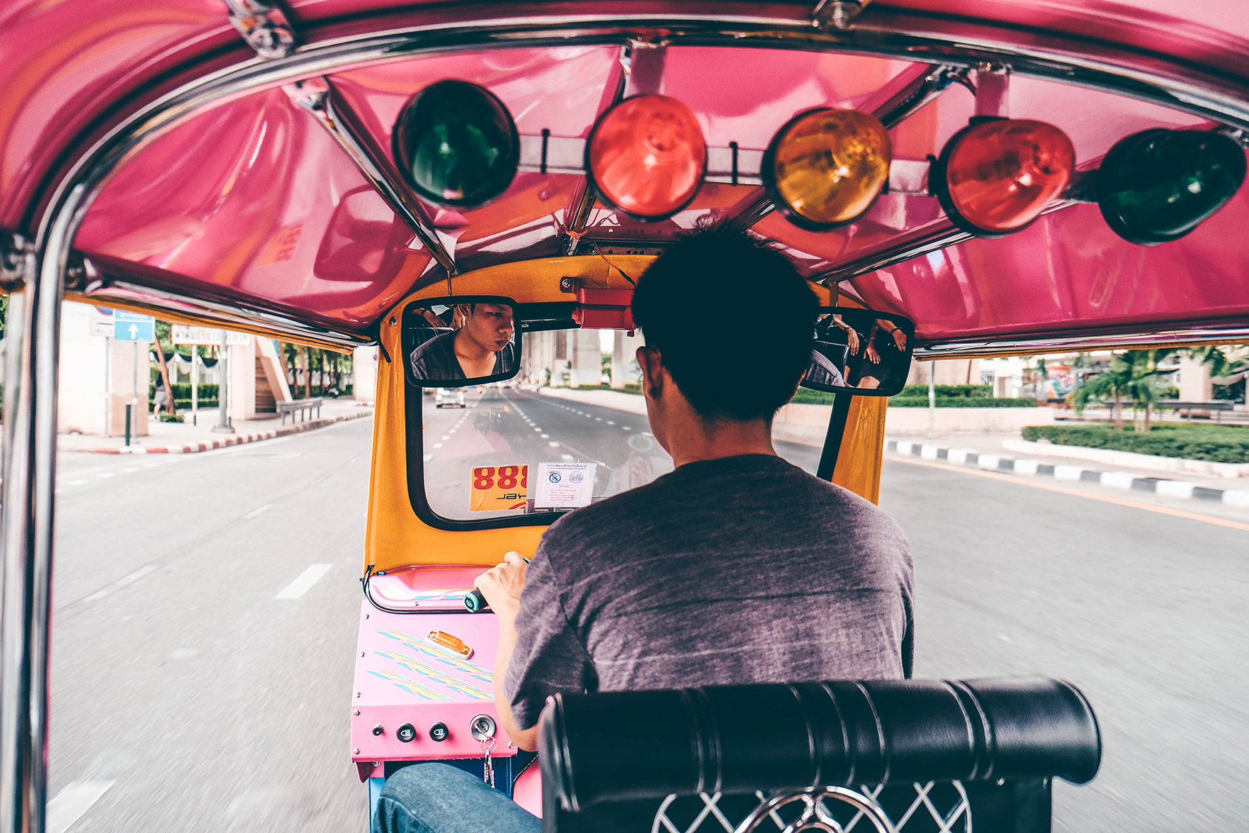 Man driving a pink tuk tuk through Bangkok