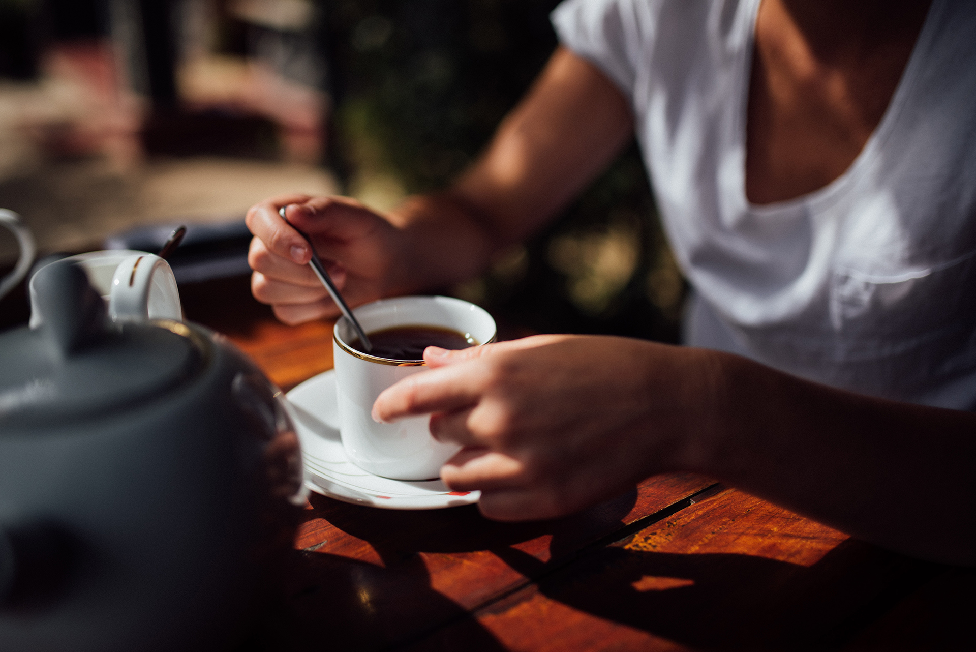 A person holding white ceramic cup filled with a dark liquid