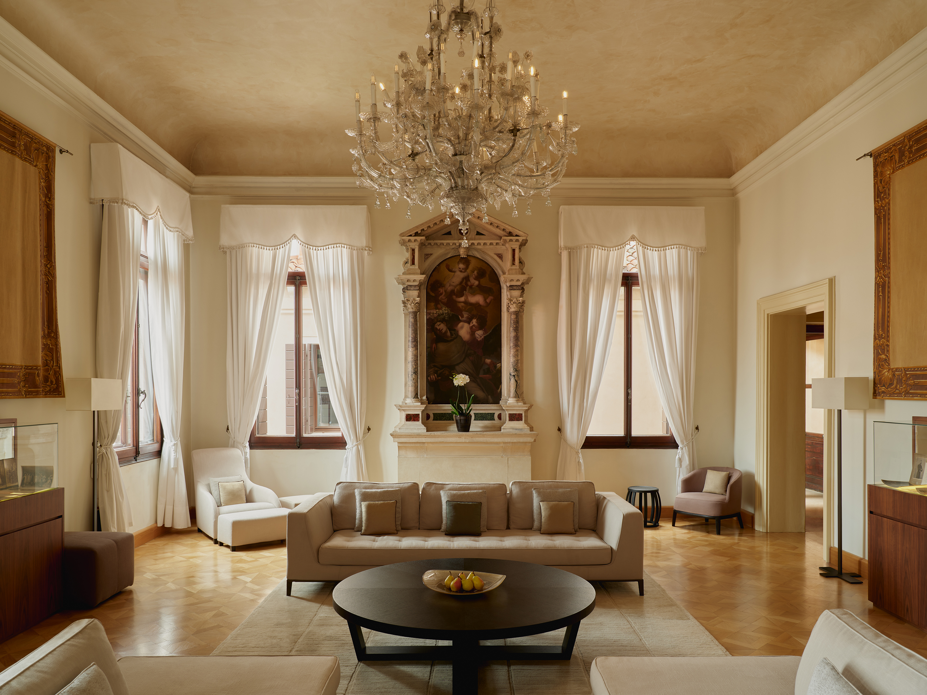 A bright high room featuring comfy furniture, a chandelier and detailed wall painting
