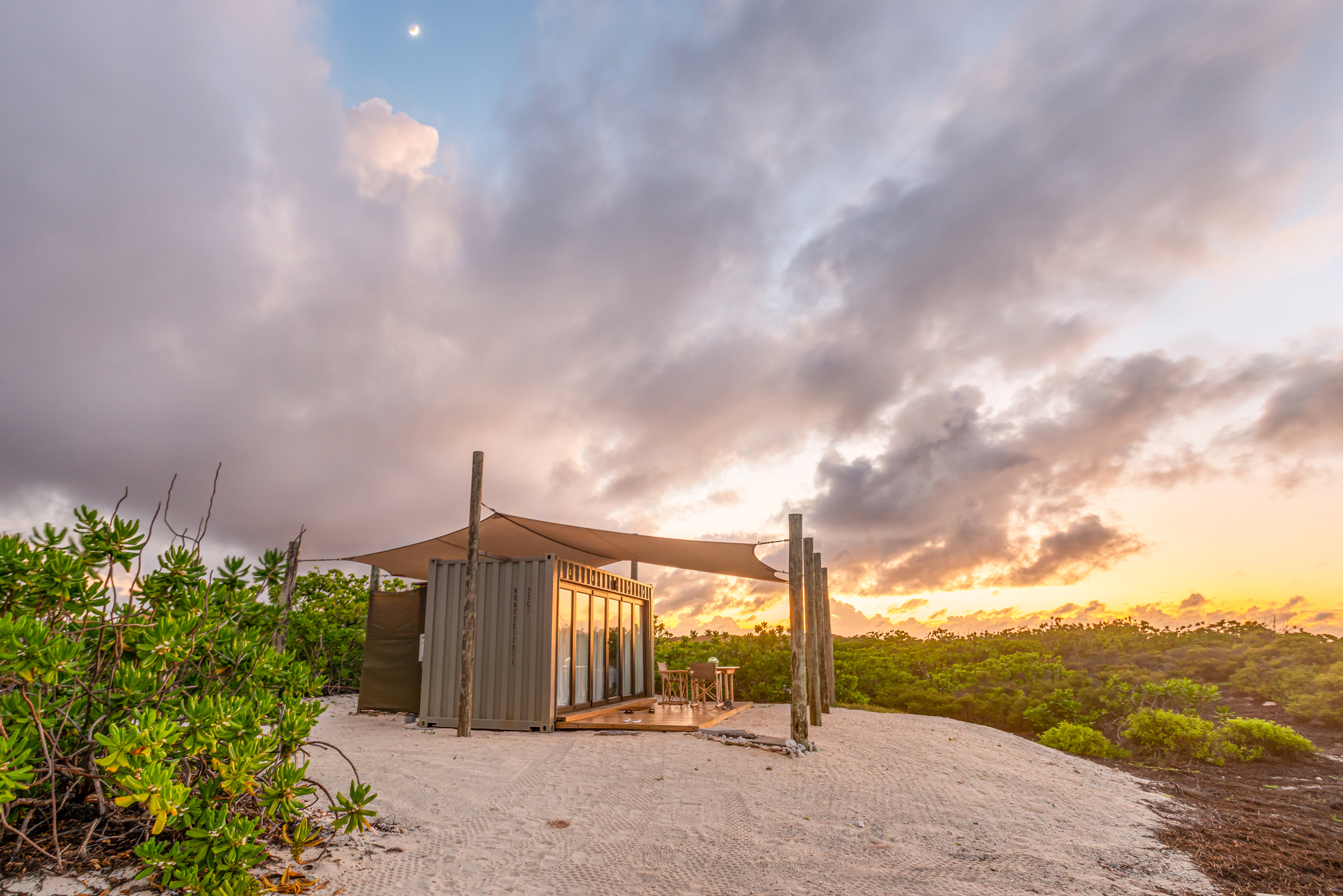 A converted shipping container with cabana at sunset