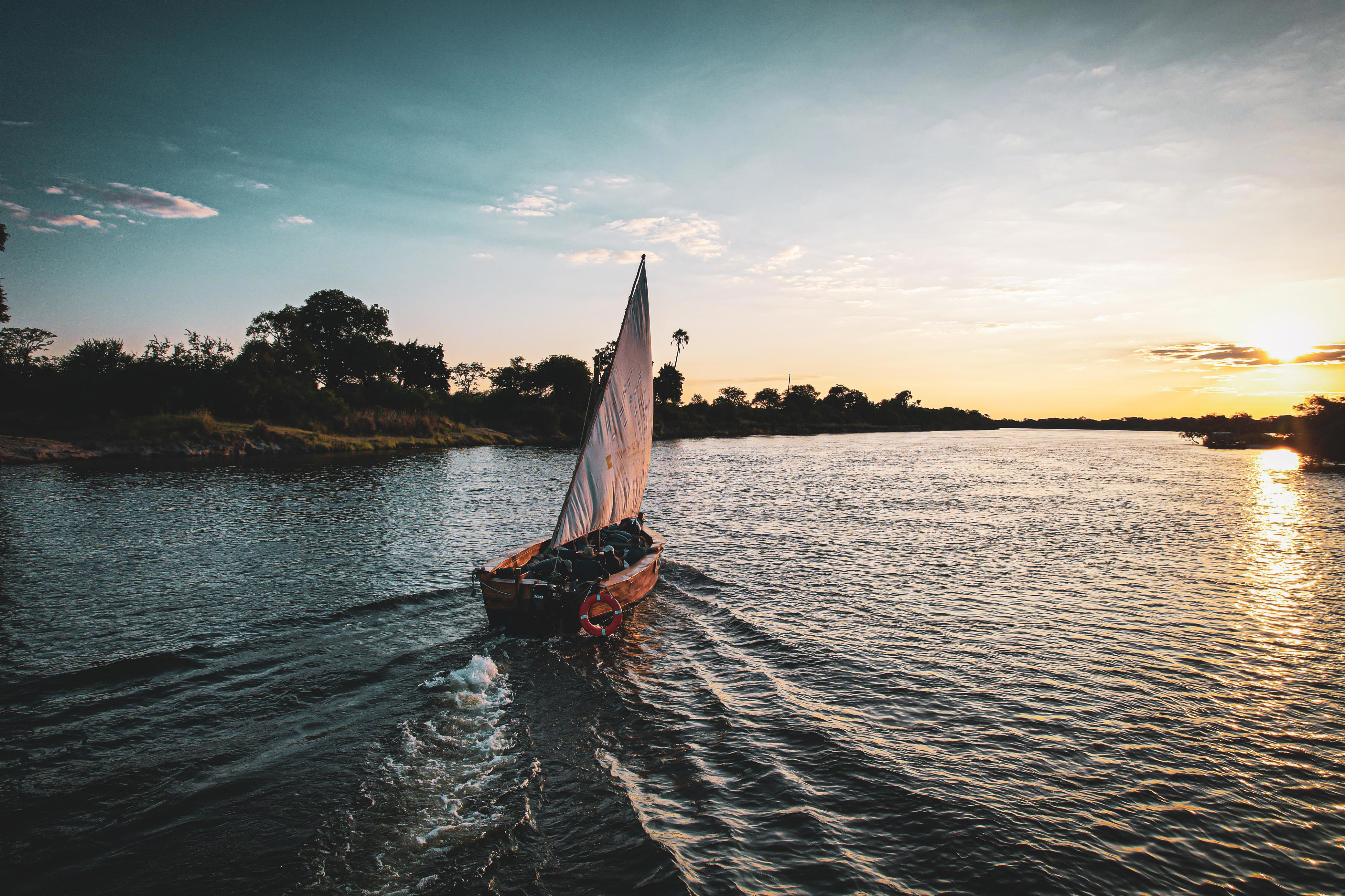A dhow boat drifting along the Zambezi river towards the sunset on the horizon