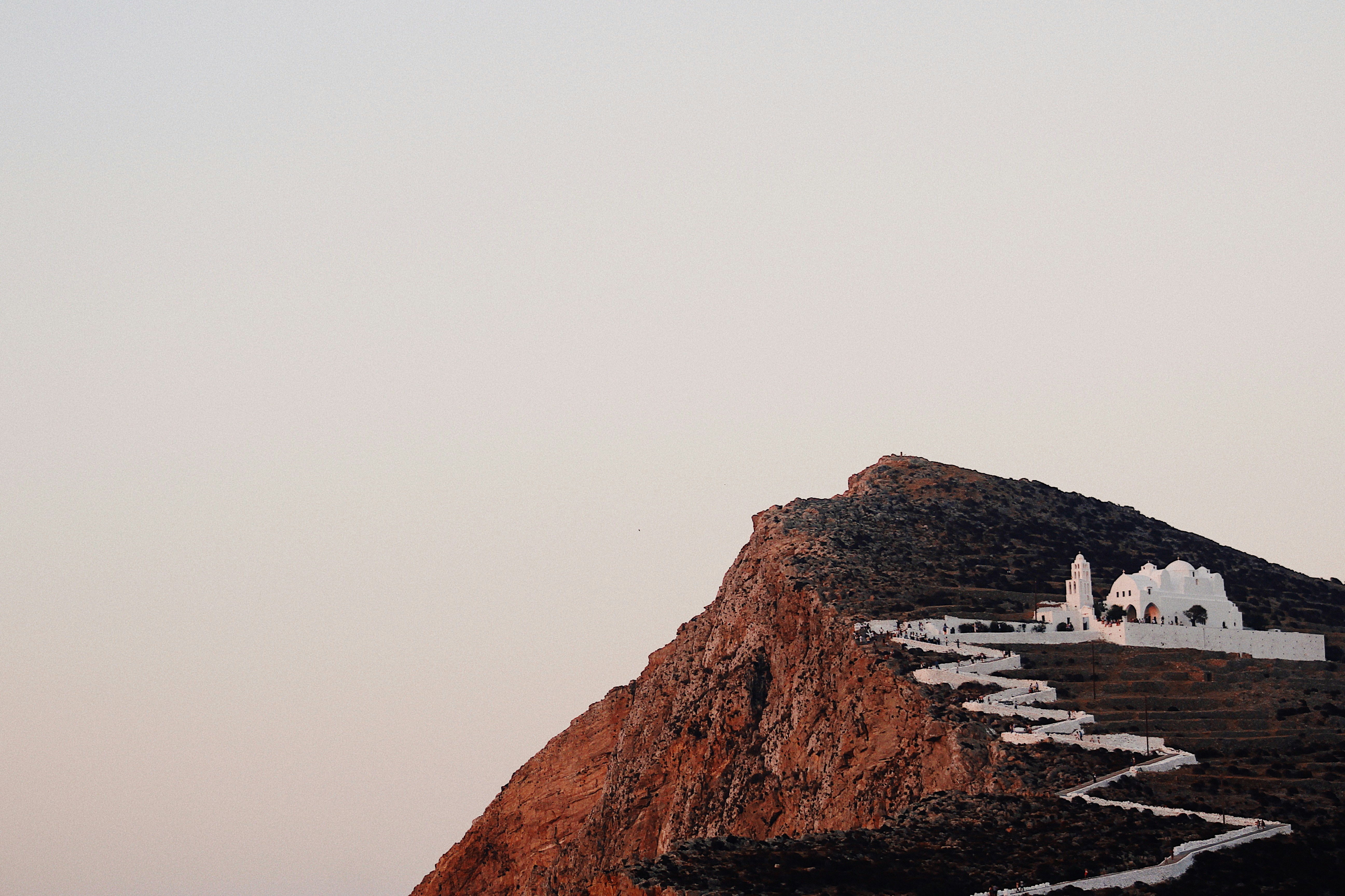 Hill top with white pathway leading up to a Chora on Folegandros at sunset