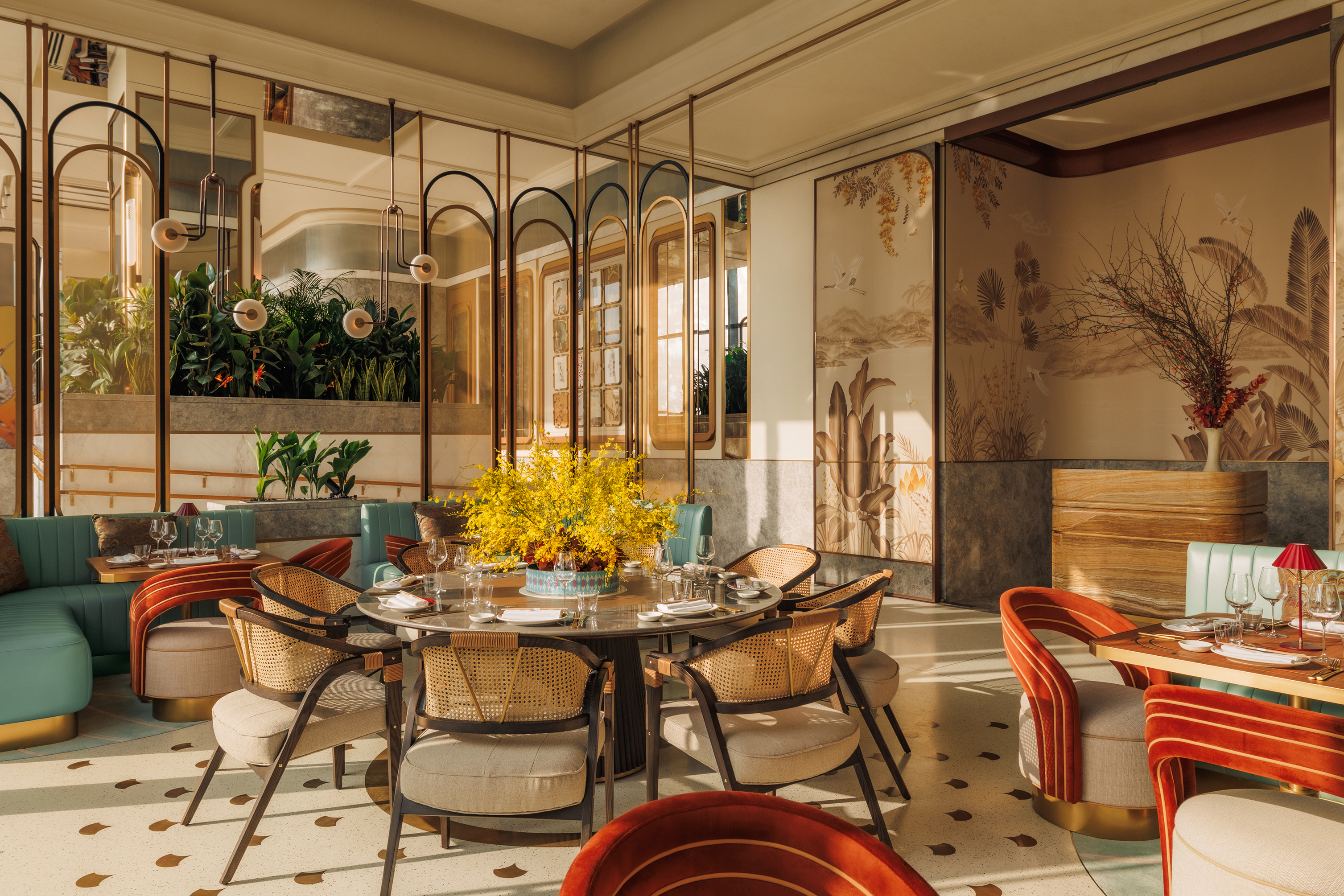 The decadant pan-Asian restaurant at Jumeriah Marsa Al Arab with plush circular dining tables and a statement light fixture surrounded by ornately decorated walls