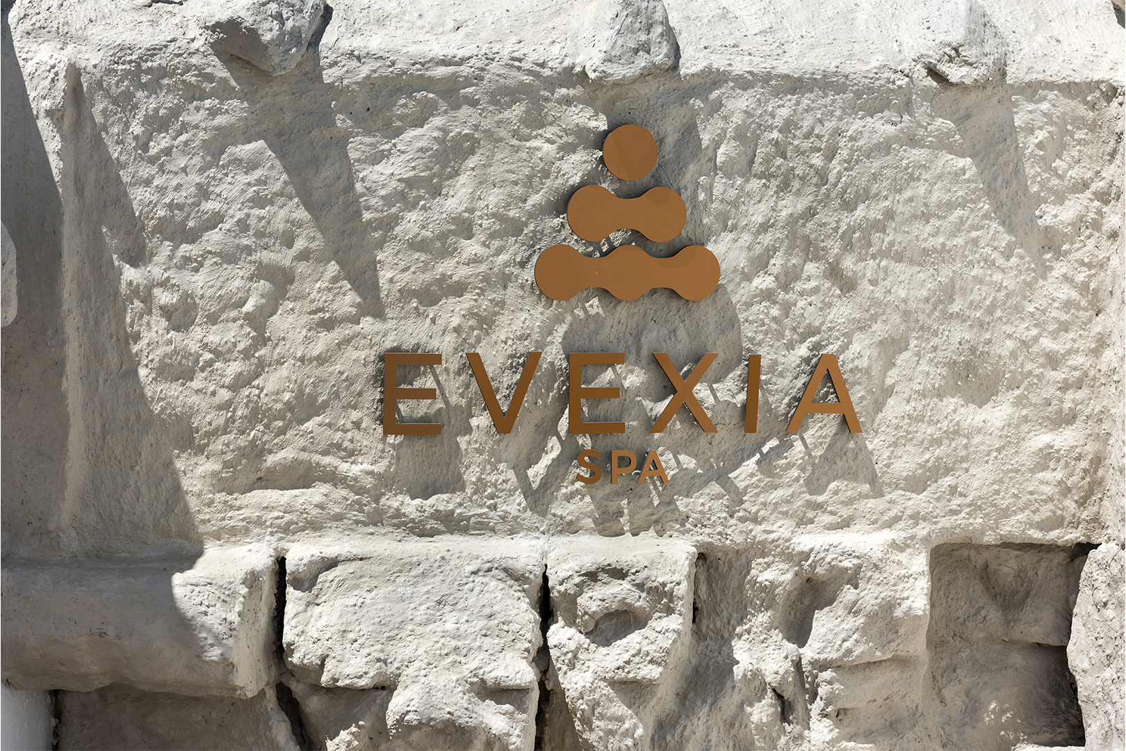 A whitewash wall made of rugged stone holds a sign for the 'Evexia Spa'
