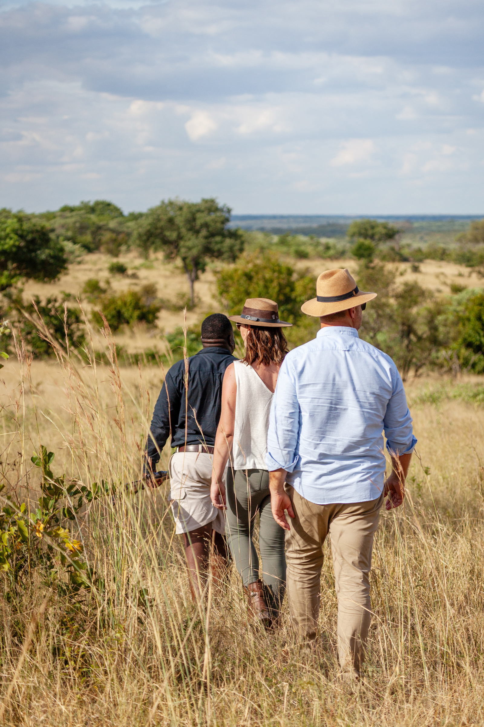 Couple in chic safari attire on a walking safari through the grassland with a local guide