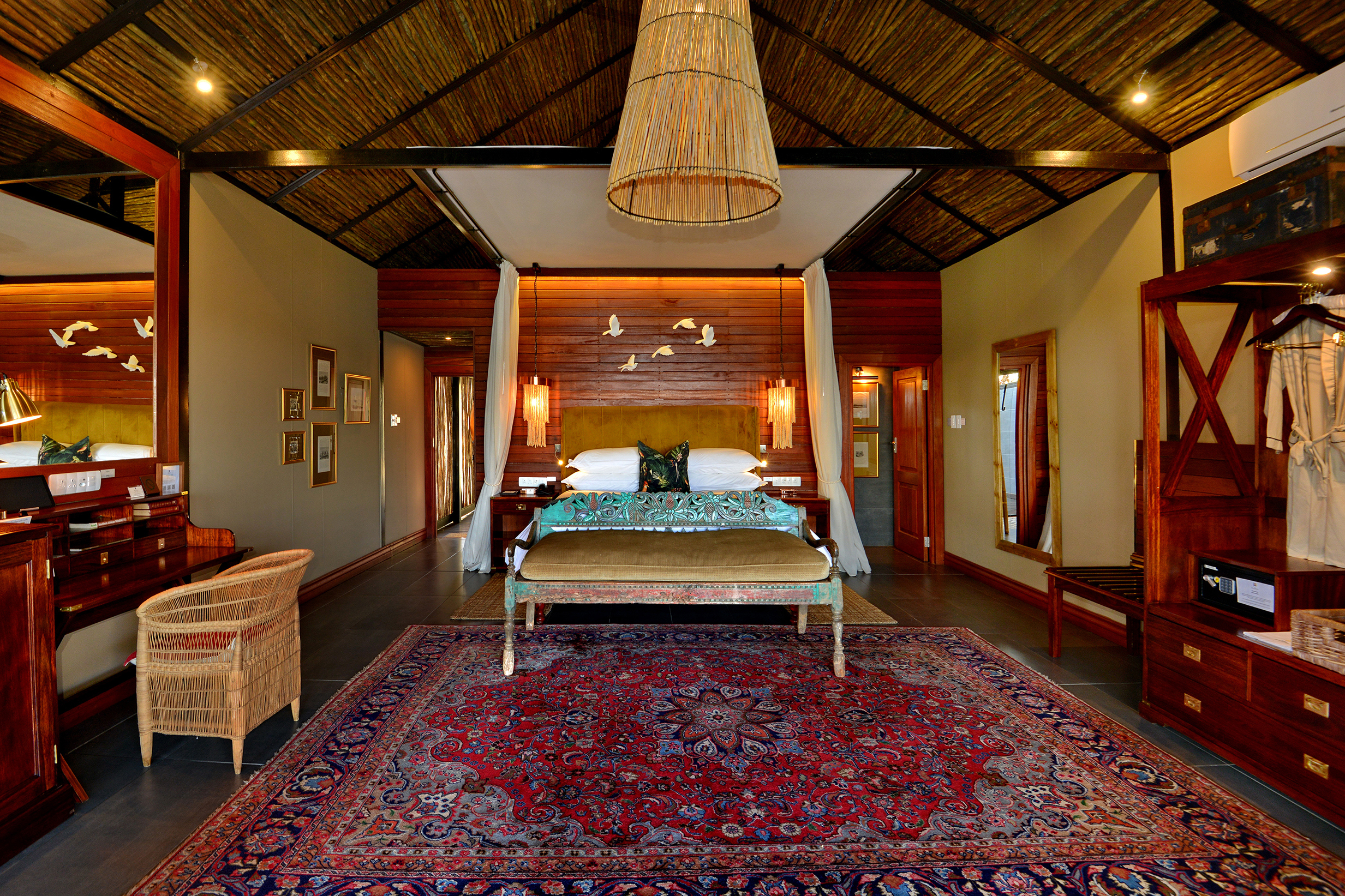 A warm, rustic bedroom at Mukwa River Lodge featuring a large bed, wooden accents, elegant decor, and cozy furnishings