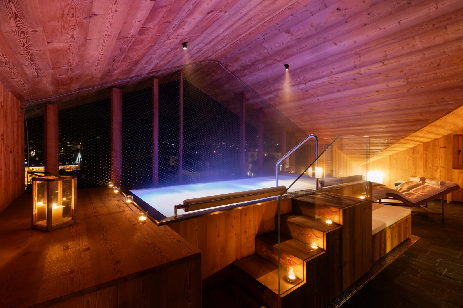 Jacuzzi in the spa lit up at night with steam riding from the water
