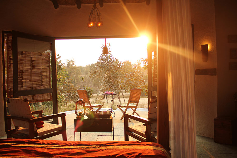Asia, India, Flame of the forest, sunlight shining into a bedroom through open double doors that lead to chairs on a terrace