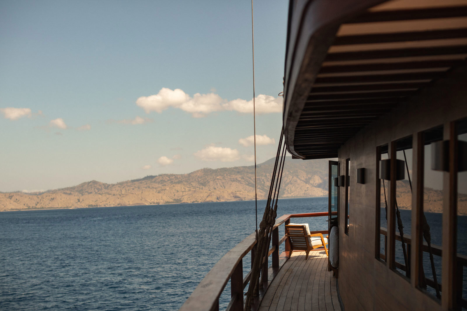 The starboard side of Vela yacht with a chair sat in the sun