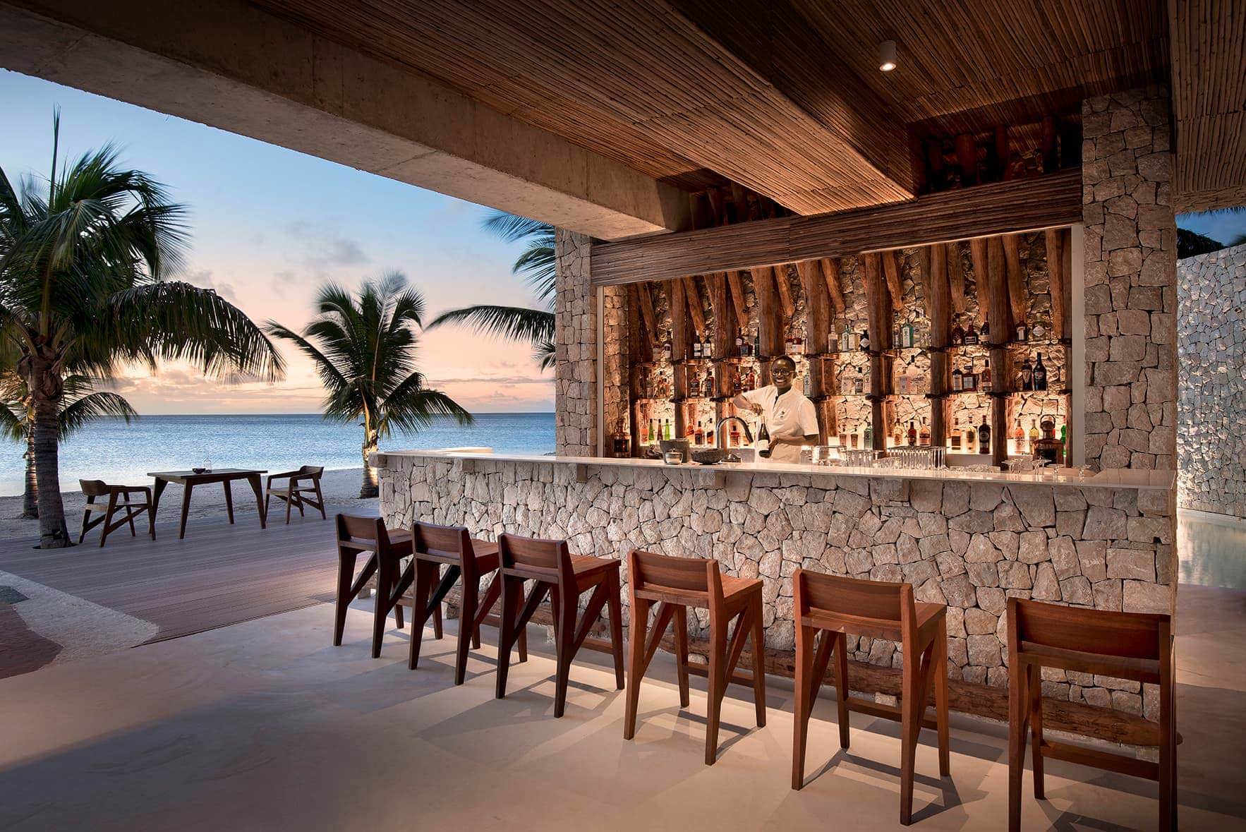 Bartender smiling behind bar lined with chairs