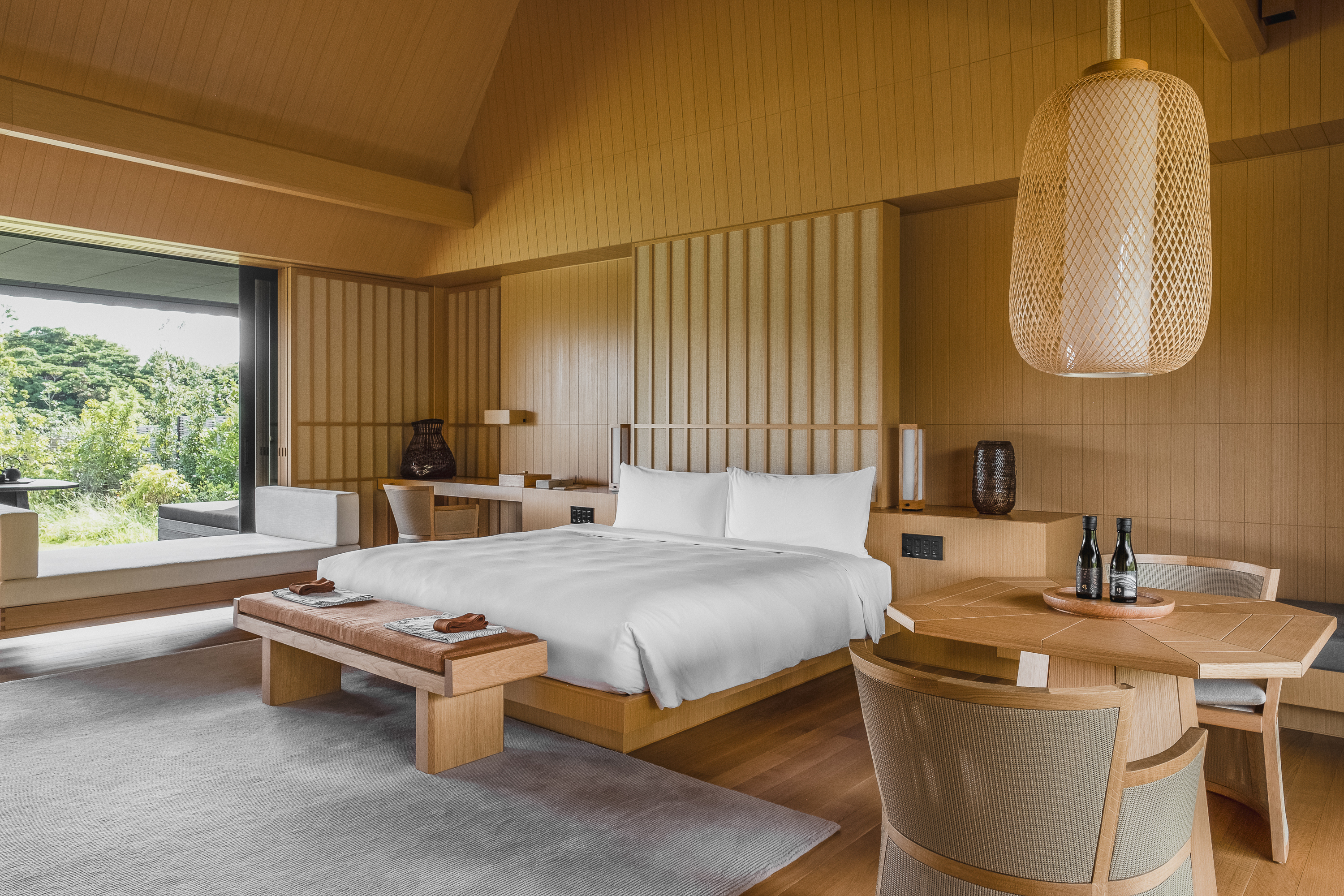 A room in the Tsuki Villa at Amanemu featuring a large bed and small dining table made from pale wood