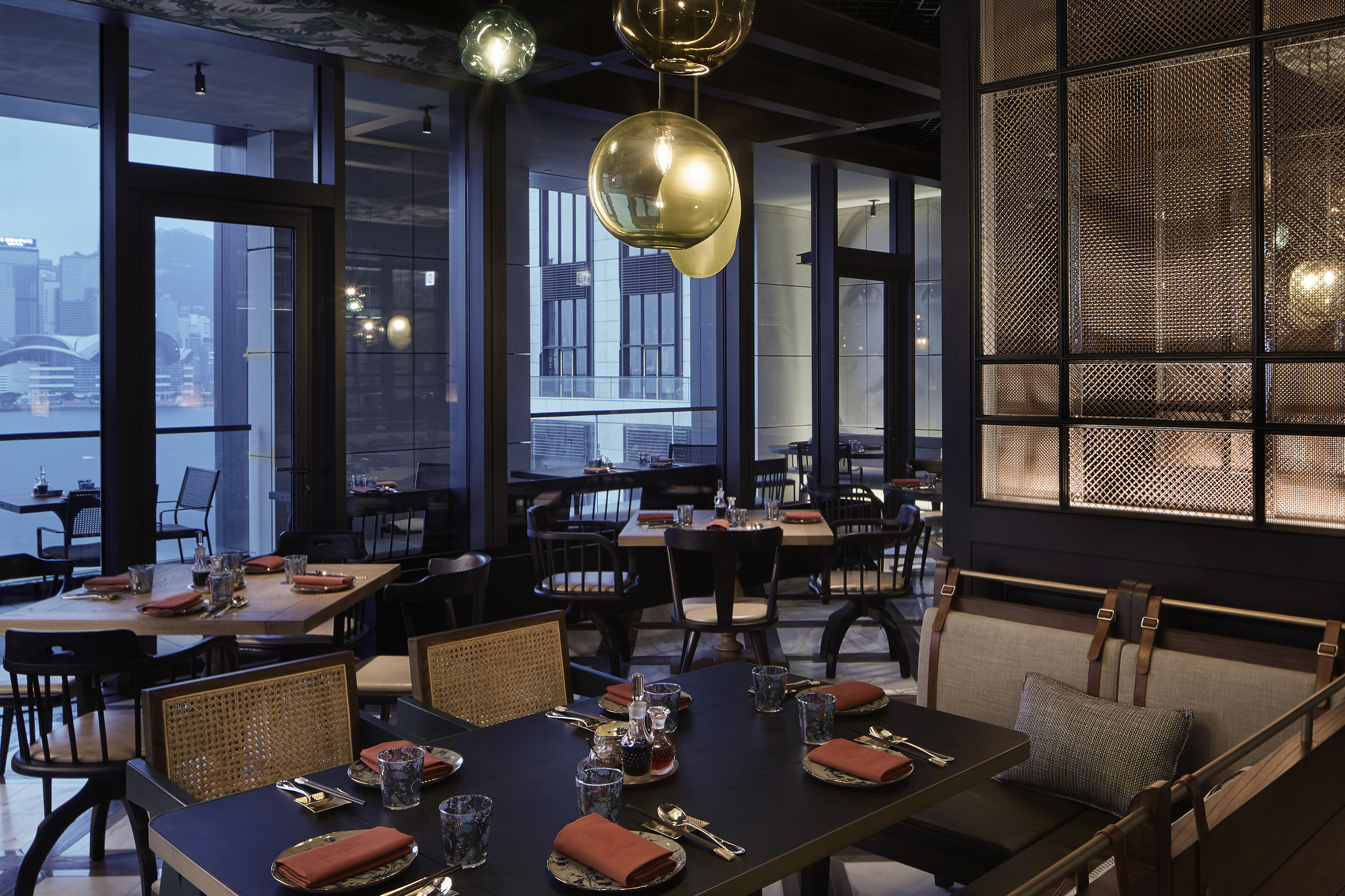 The modern dining room of The Legacy House at Rosewood Hong Kong featuring sleek furniture and moody lighting