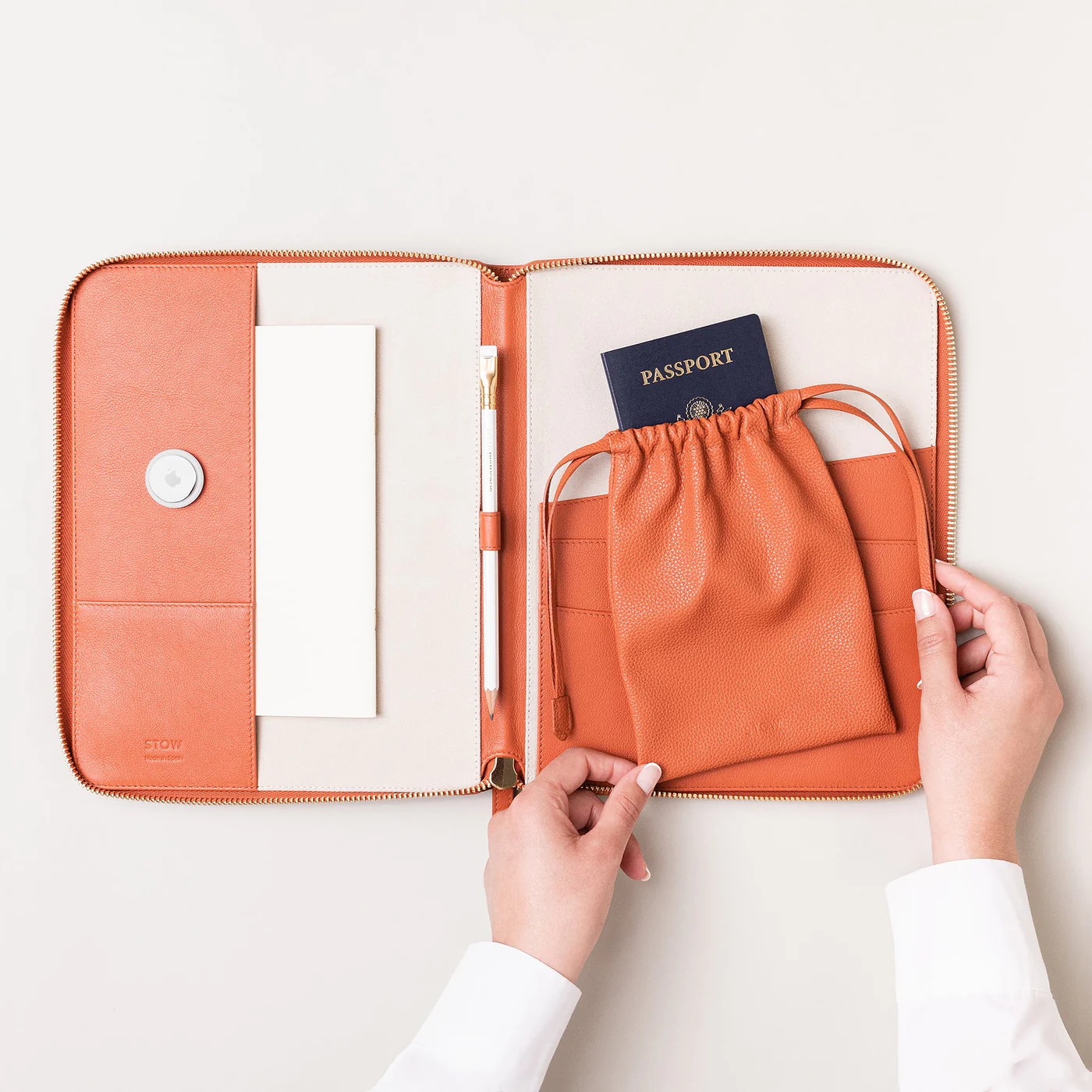 Stow wallet open with pencil, airtag, and passport