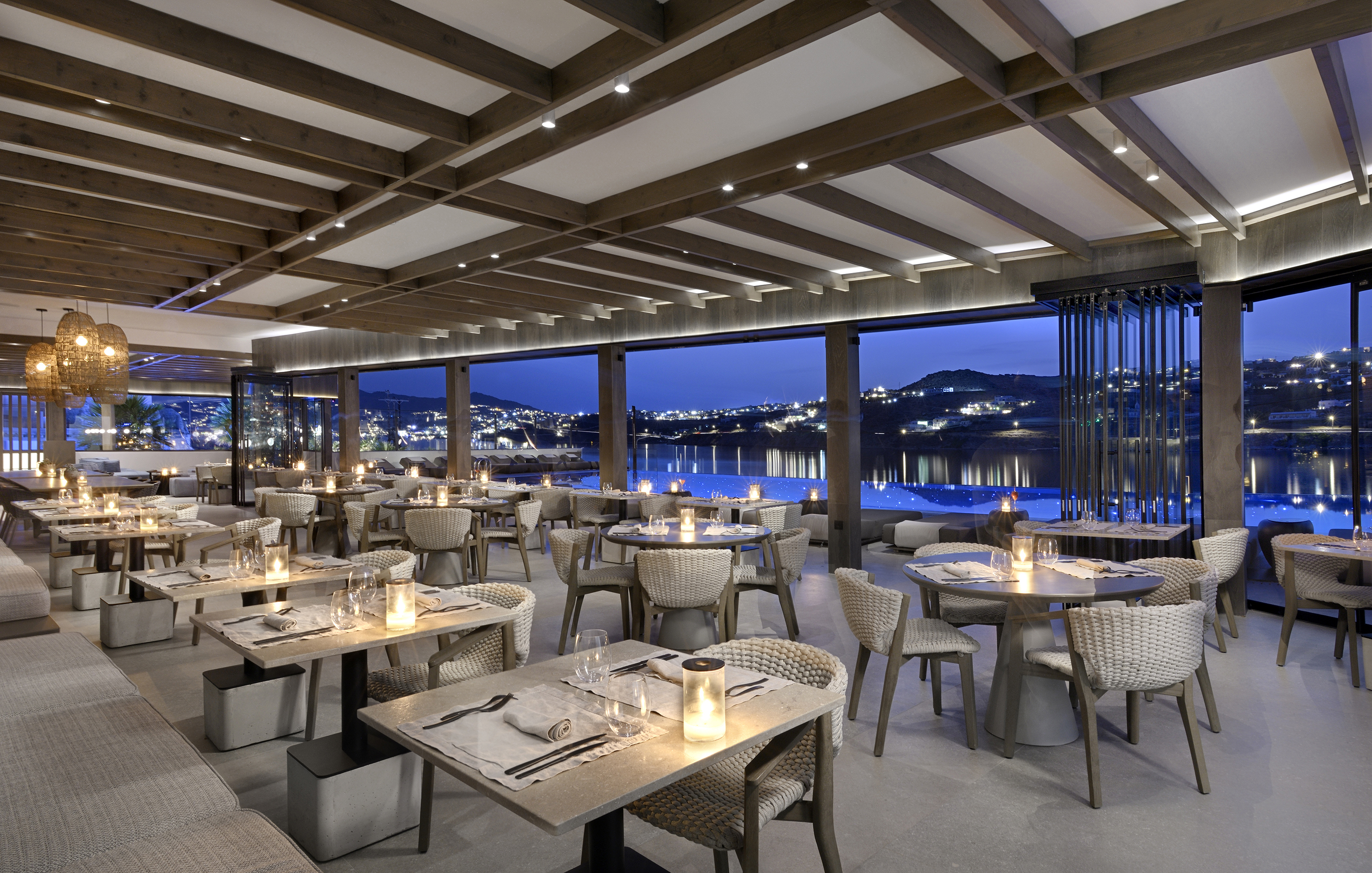 Dining tables with lit candles in the Cove Restaurant at Aeonic Suites & Spa