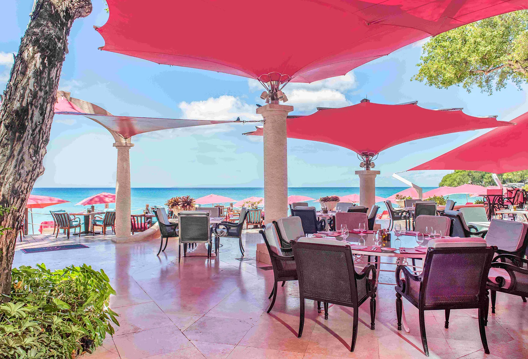 Caribbean, Barbados, Sandy Lane, dining tables at Bajan Blue shaded by pink canopies with a sea view 
