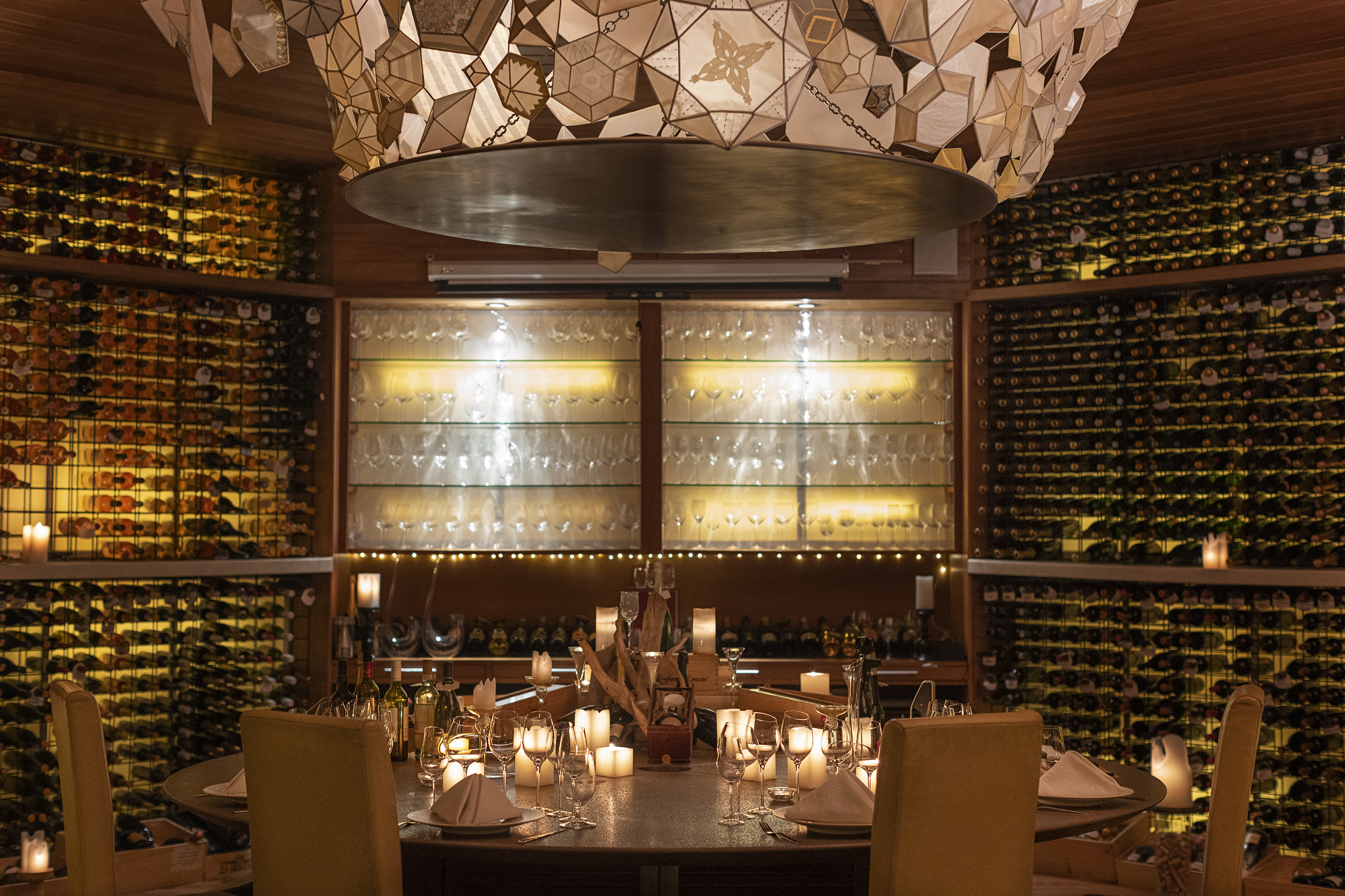 The Vinum wine cellar at Huvafen Fushi featuring a circular table set for dinner with wine bottles lining the walls