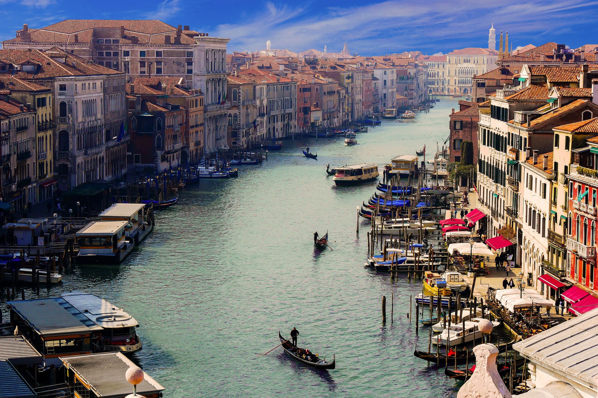 An aerial view of a Venice canal flanked by classic buildings as gondolas sail by