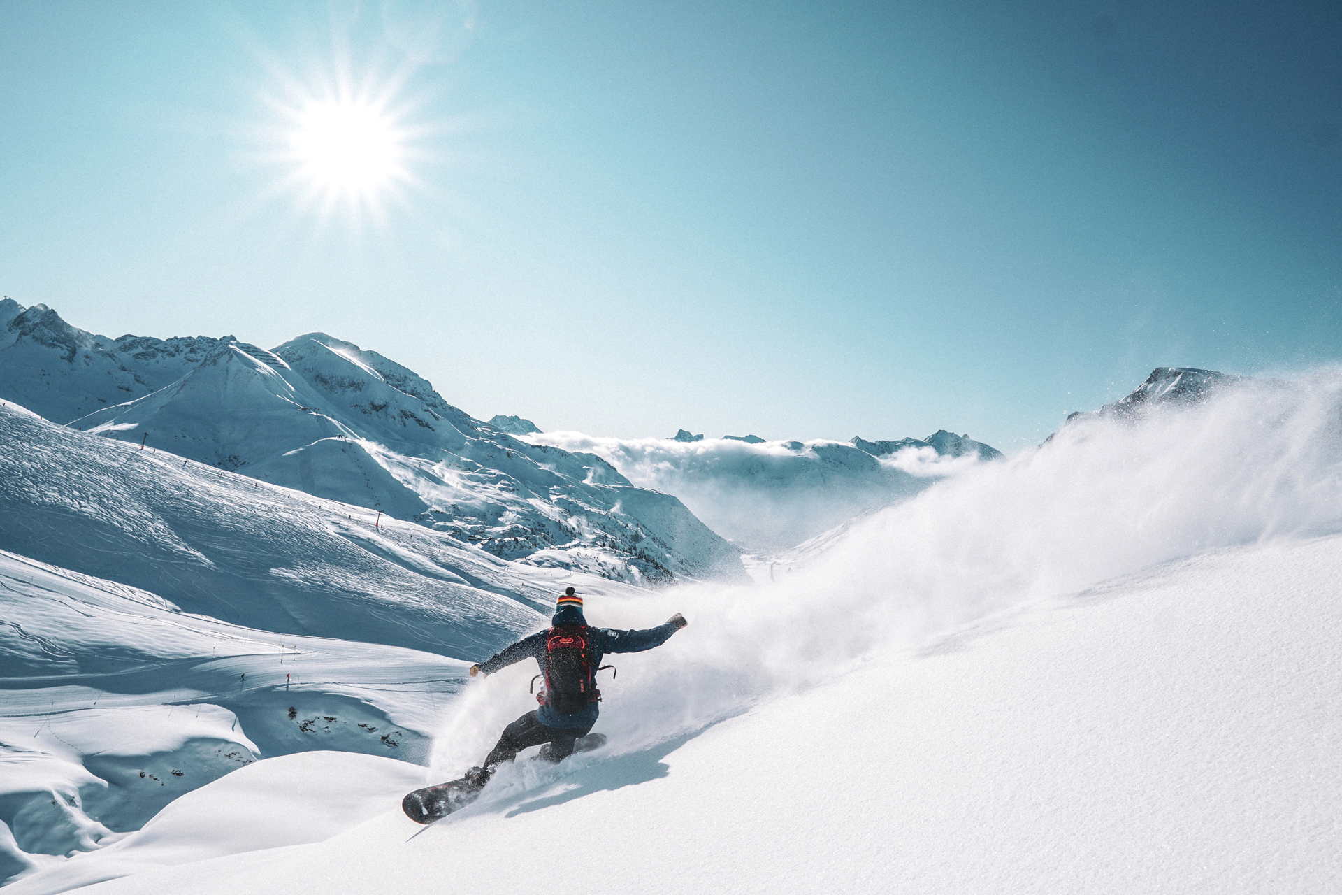 A man riding a snowboard down the side of a snowy hill