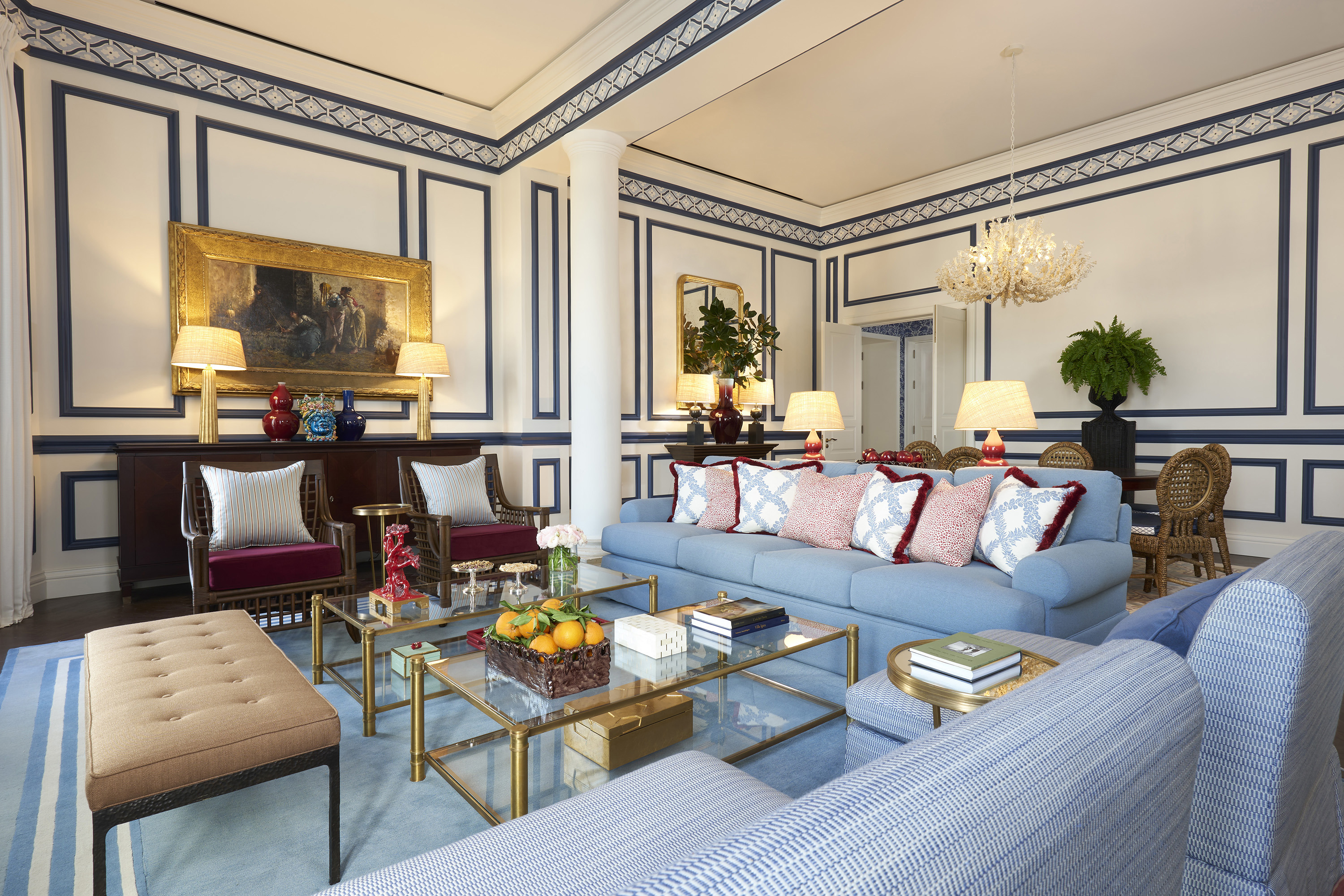 Living room with blue sofas, gold and glass coffee tables, and decorative elements creating a luxurious interior space.