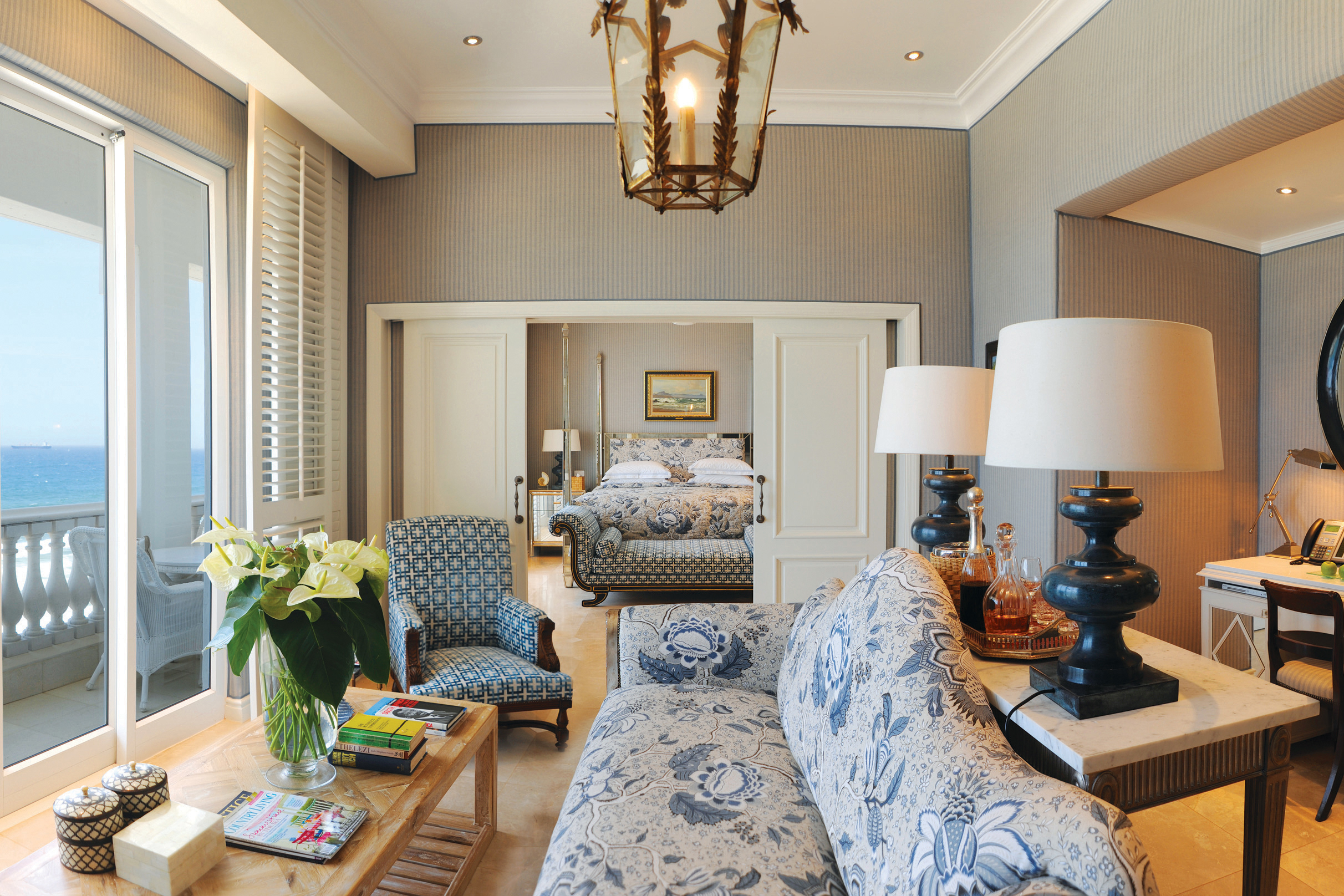 A lavish suite lounge at The Oyster Box featuring pretty patterned furniture and classic decor with a glimpse of the bedroom beyond