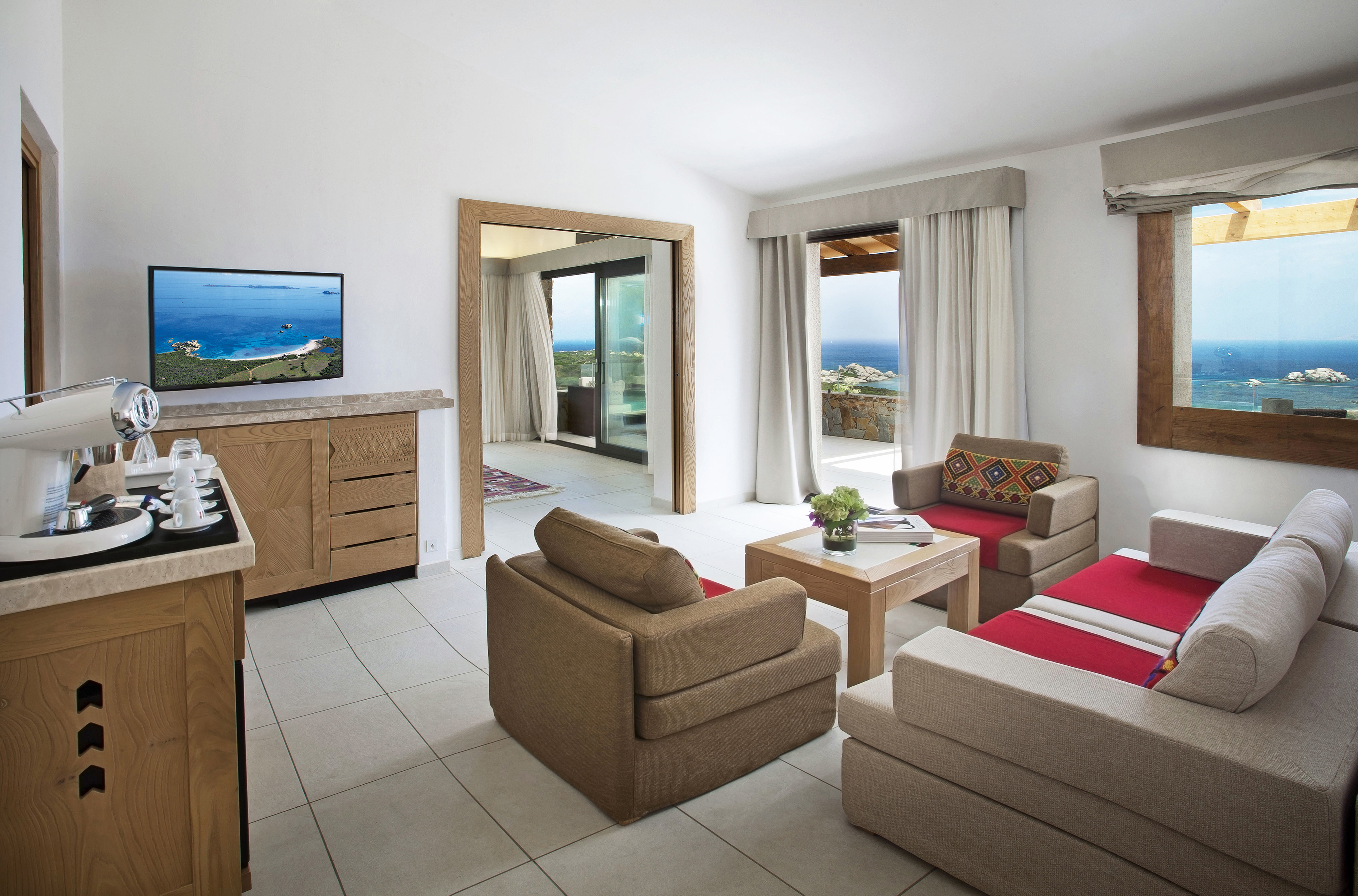 The lounge of a President Razzoli Suite in Hotel La Licciola featuring neutral furniture and ocean views