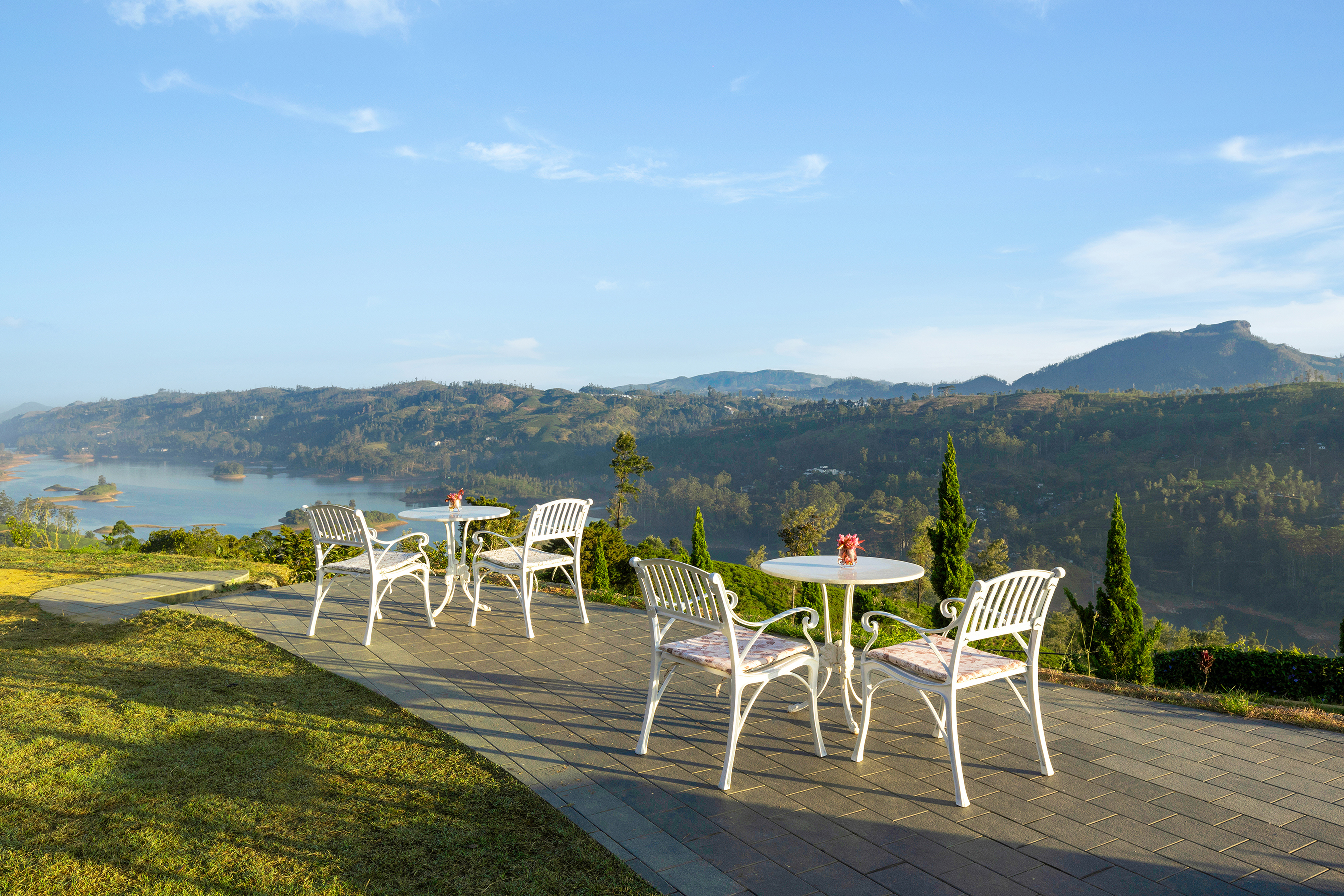 Two white bistro table sets on the terrace of Uga Halloowella overlooking the reservoir 