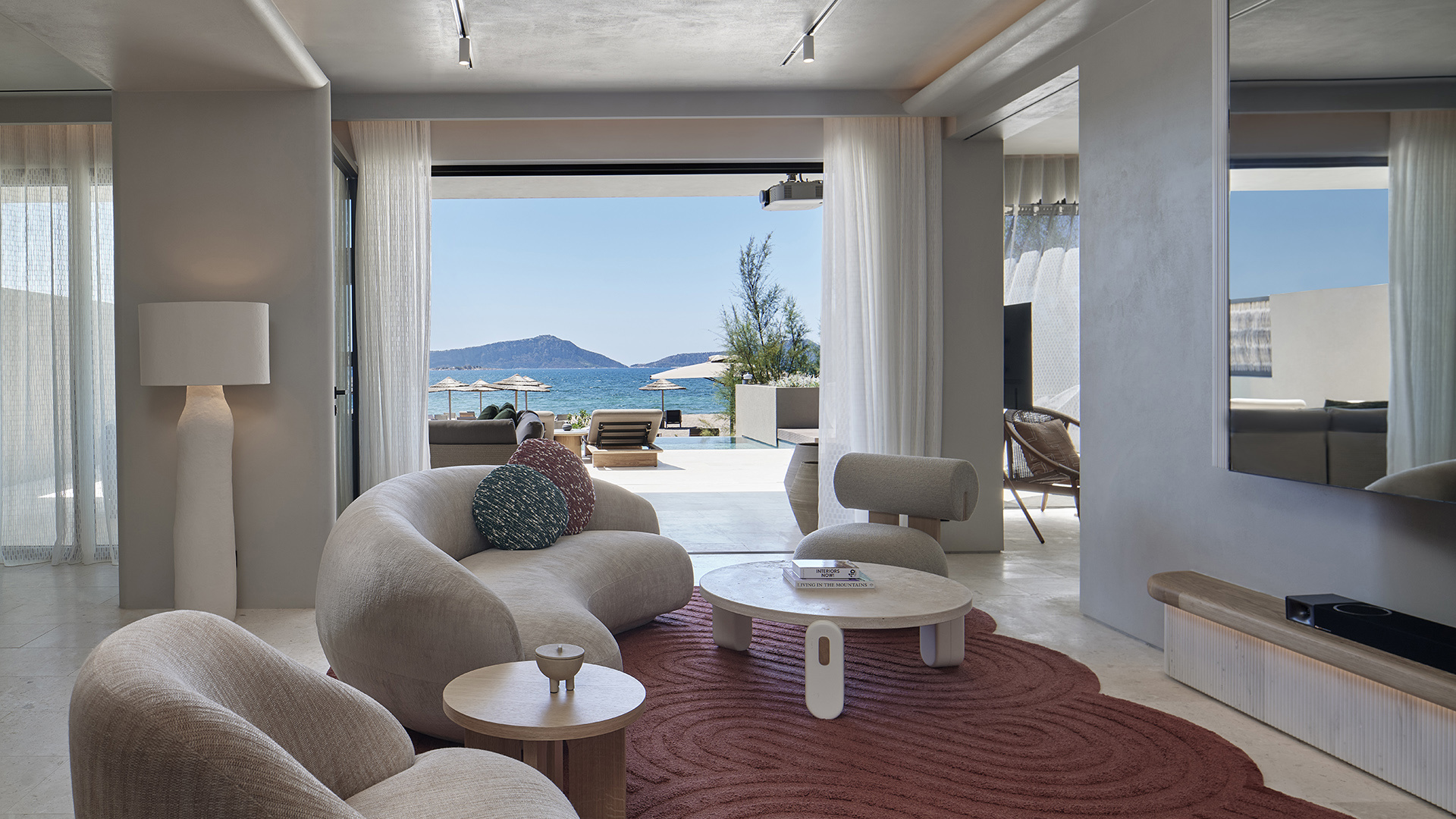 Villa lounge with cream sofas and red rug looking out onto the beach at W Costa Navarino