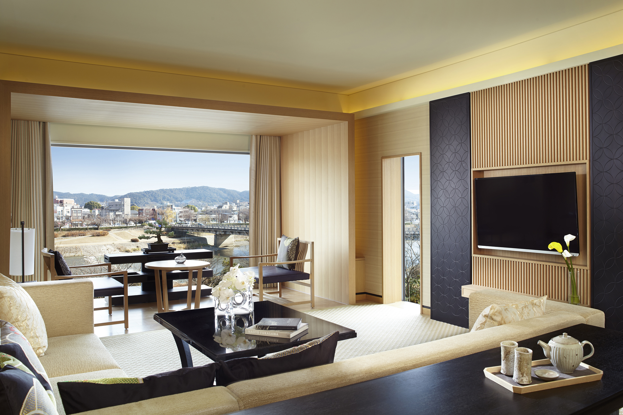 A sleek suite at the Ritz-Carlton Kyoto featuring plush furnitre and large windows with a view of the city