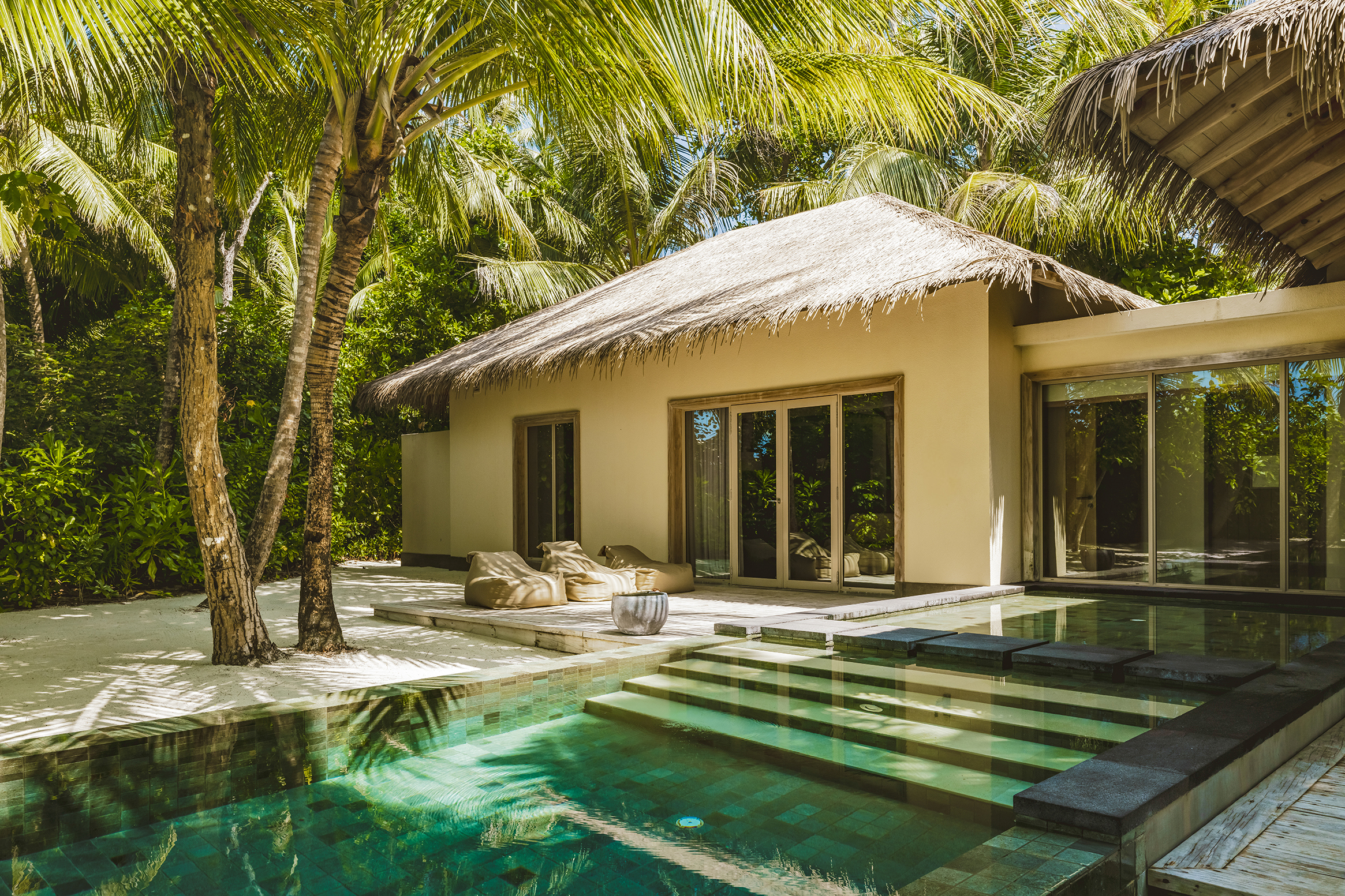 Luxurious villa with private pool surrounded by lush palm trees at InterContinental Maldives.