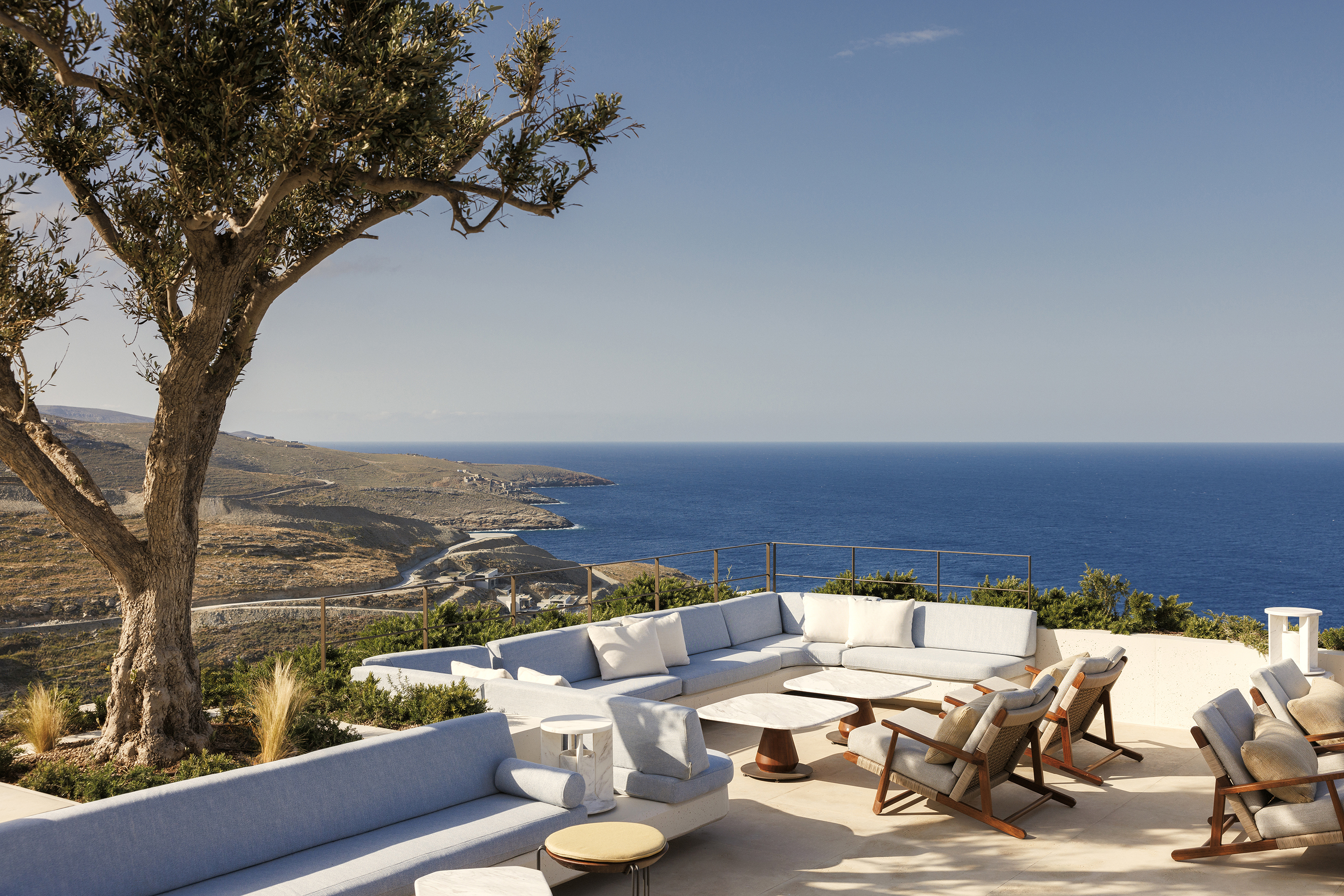 Bar terrace with white table and chairs looking out over hilly landscape and sea