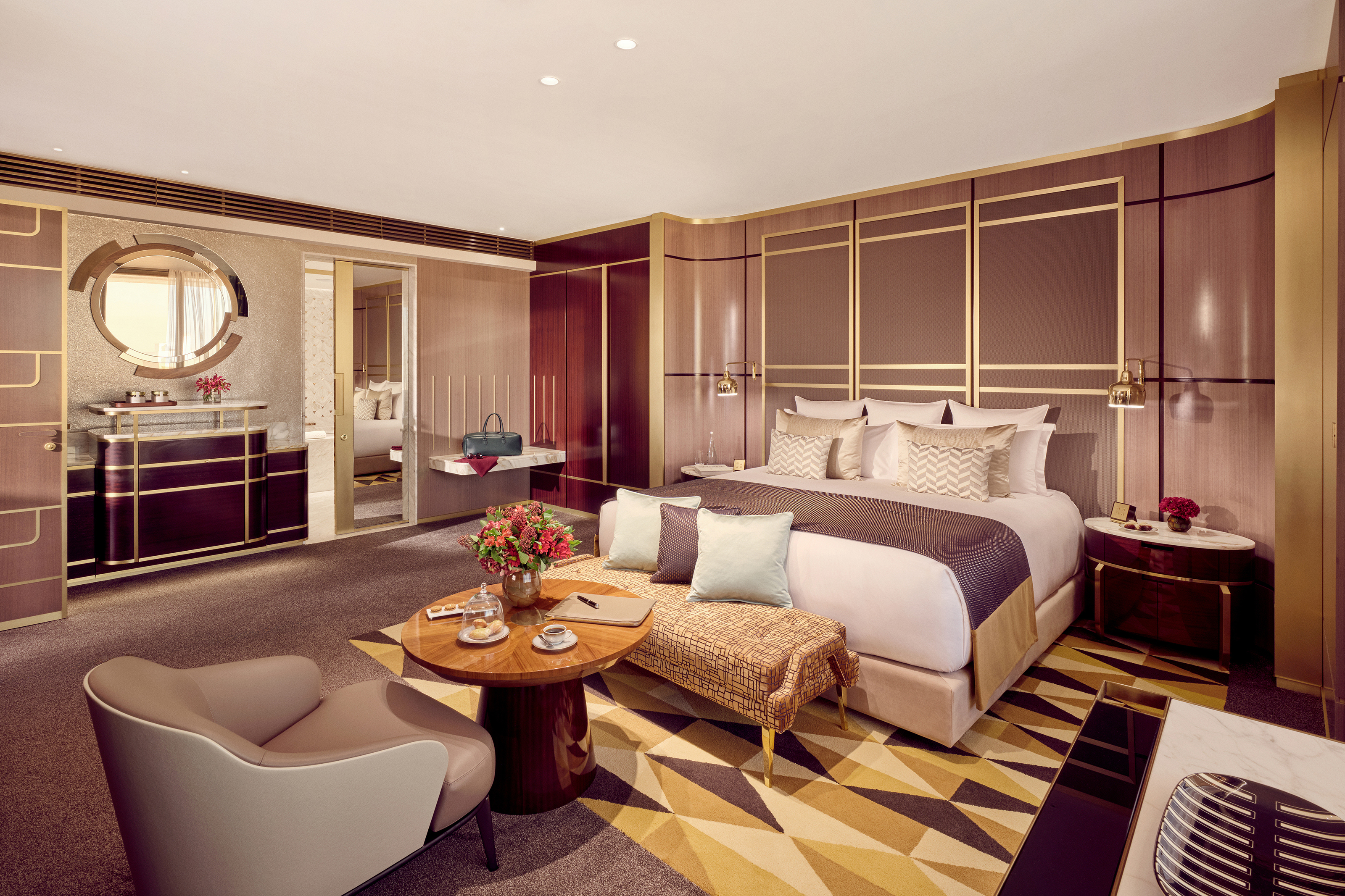 The bedroom of a suite at Royal Mansour Casablanca featuring a large bed with lavish soft furnishings, decorative walls and a glimpse of the bathroom