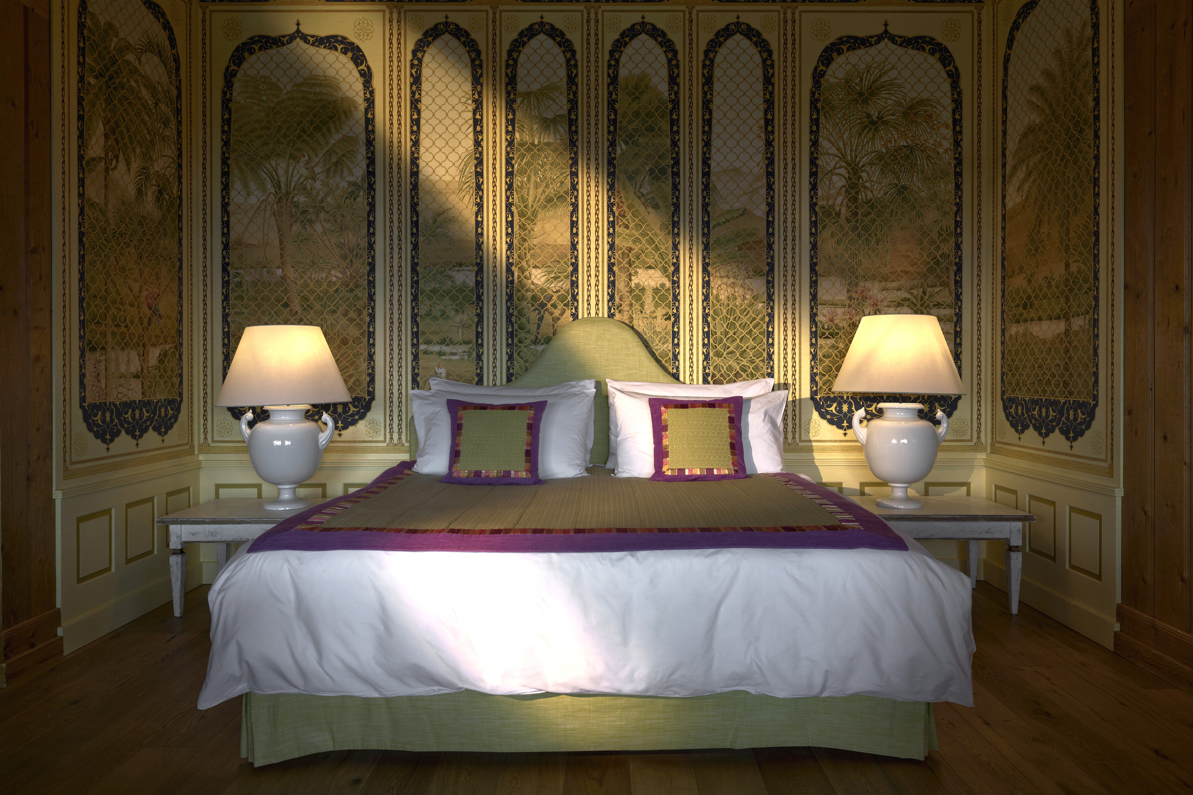 An ornate suite with plush bed flanked by lamps and decorative wall with imagery