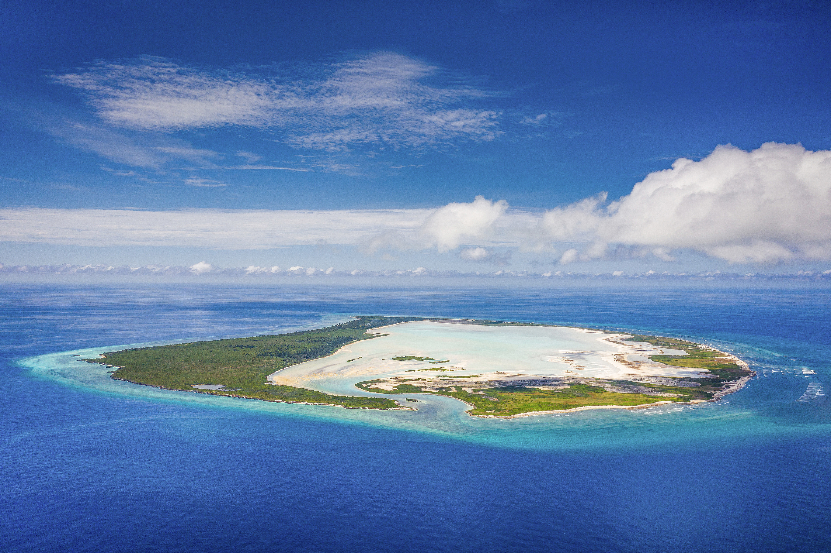 A large green island surrounded by blue ocean beneath a clear sky