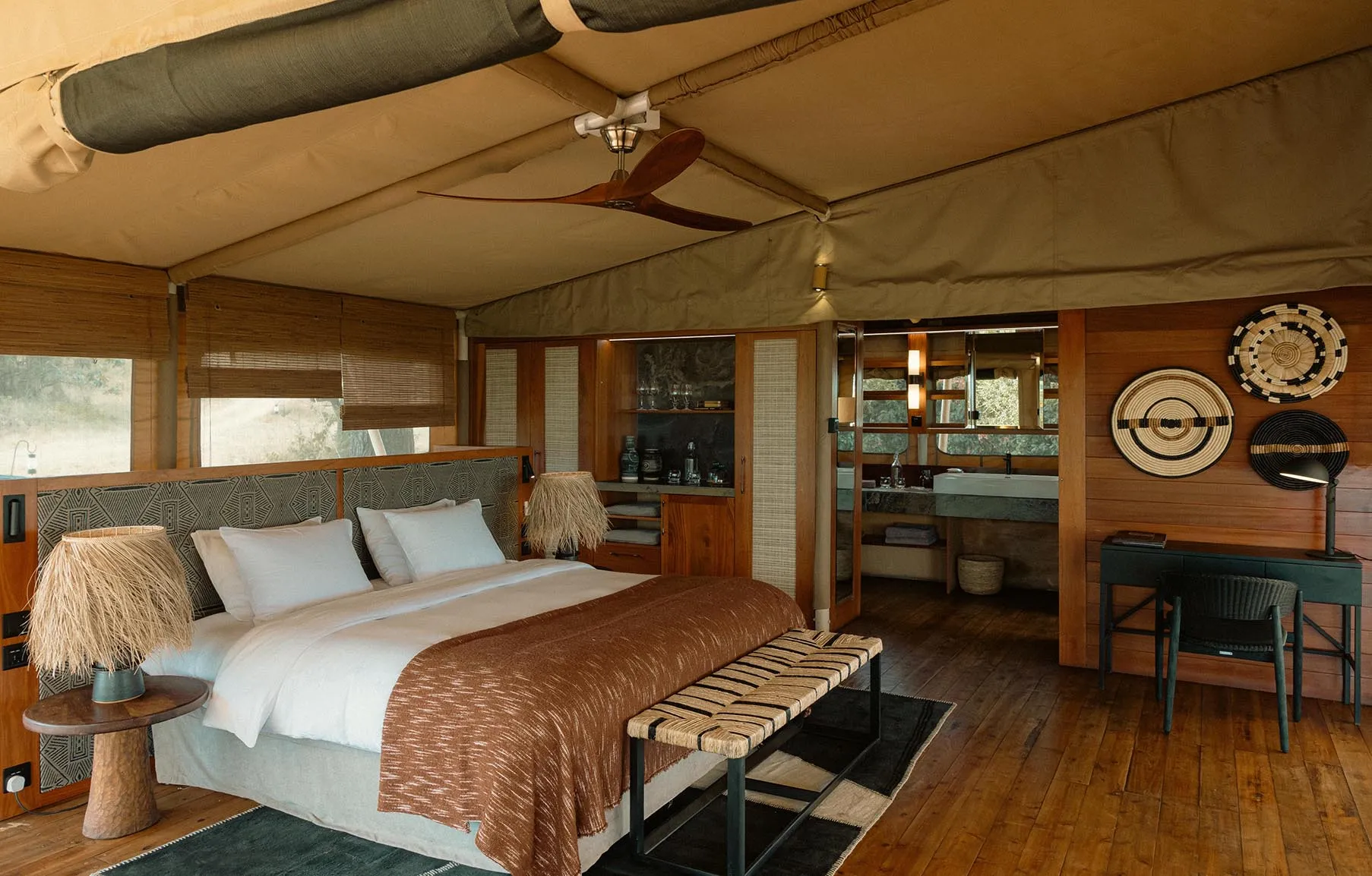 Africa, Tanzania, Serengeti Bushtops, luxury tent interior, bedroom with desk and drinks cabinet looking into bathroom