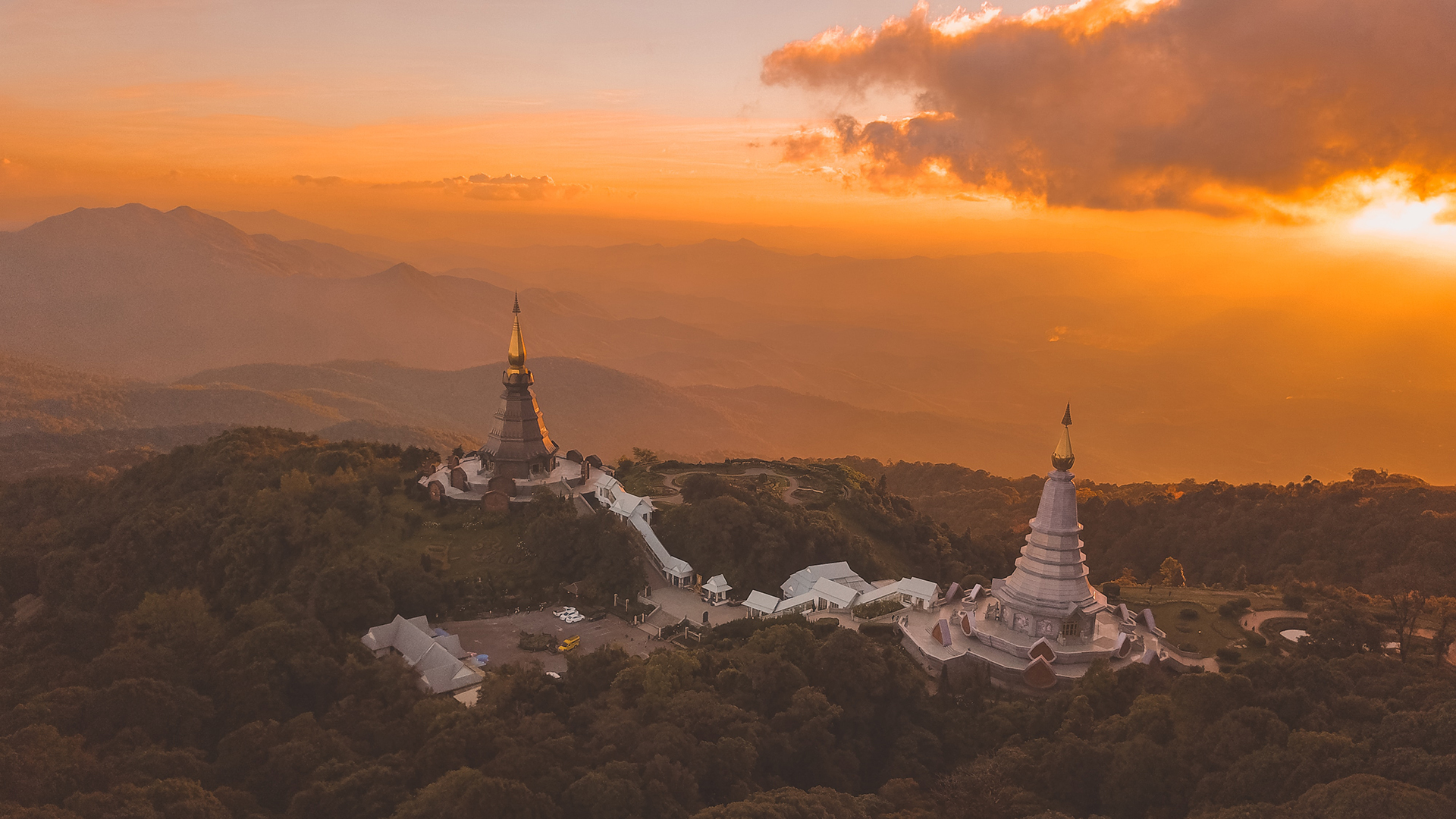 Aerial view of two monuments on a hill surrounded by trees during golden hour sunset