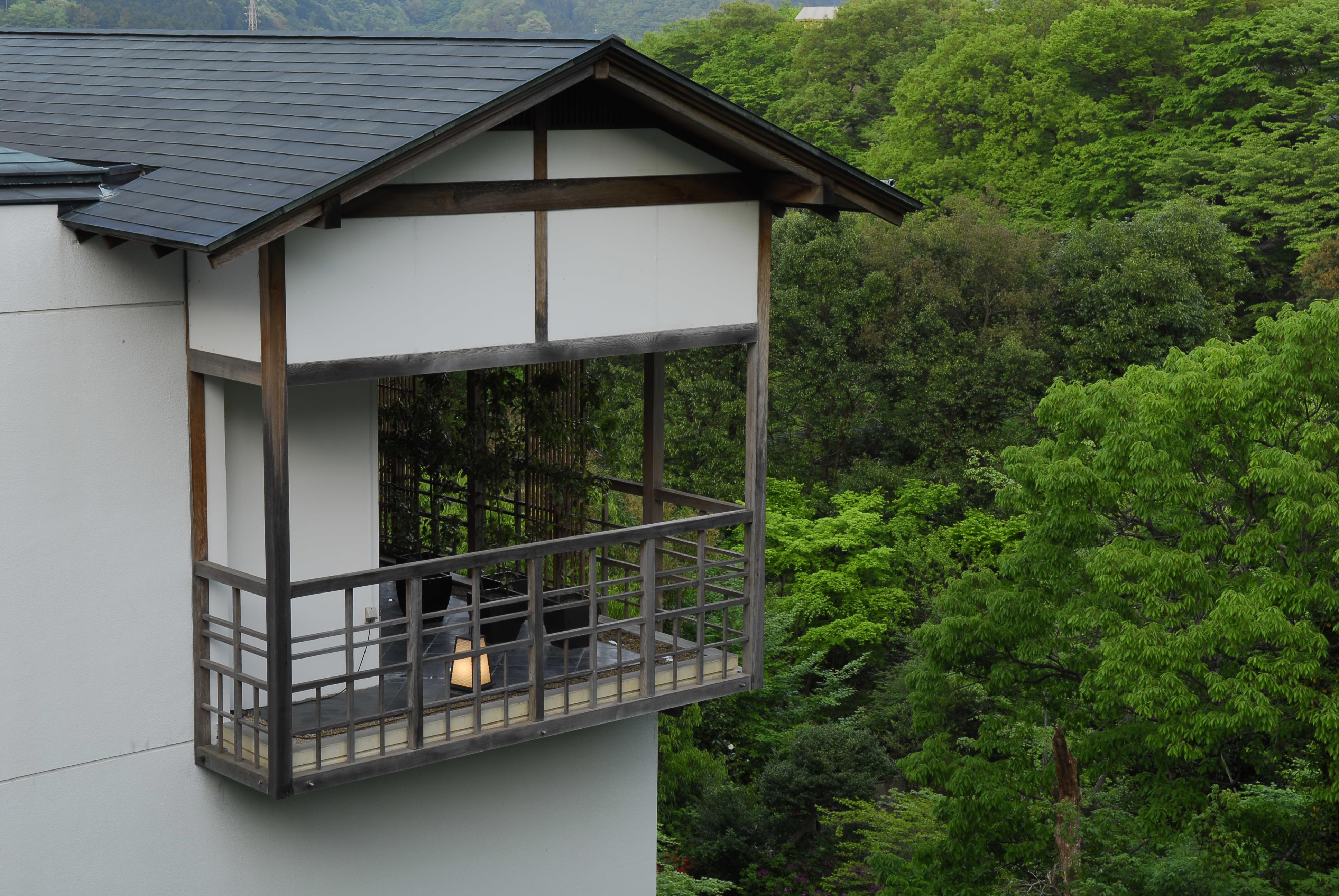 A corner balcony on a white building overlooking a dense jungle
