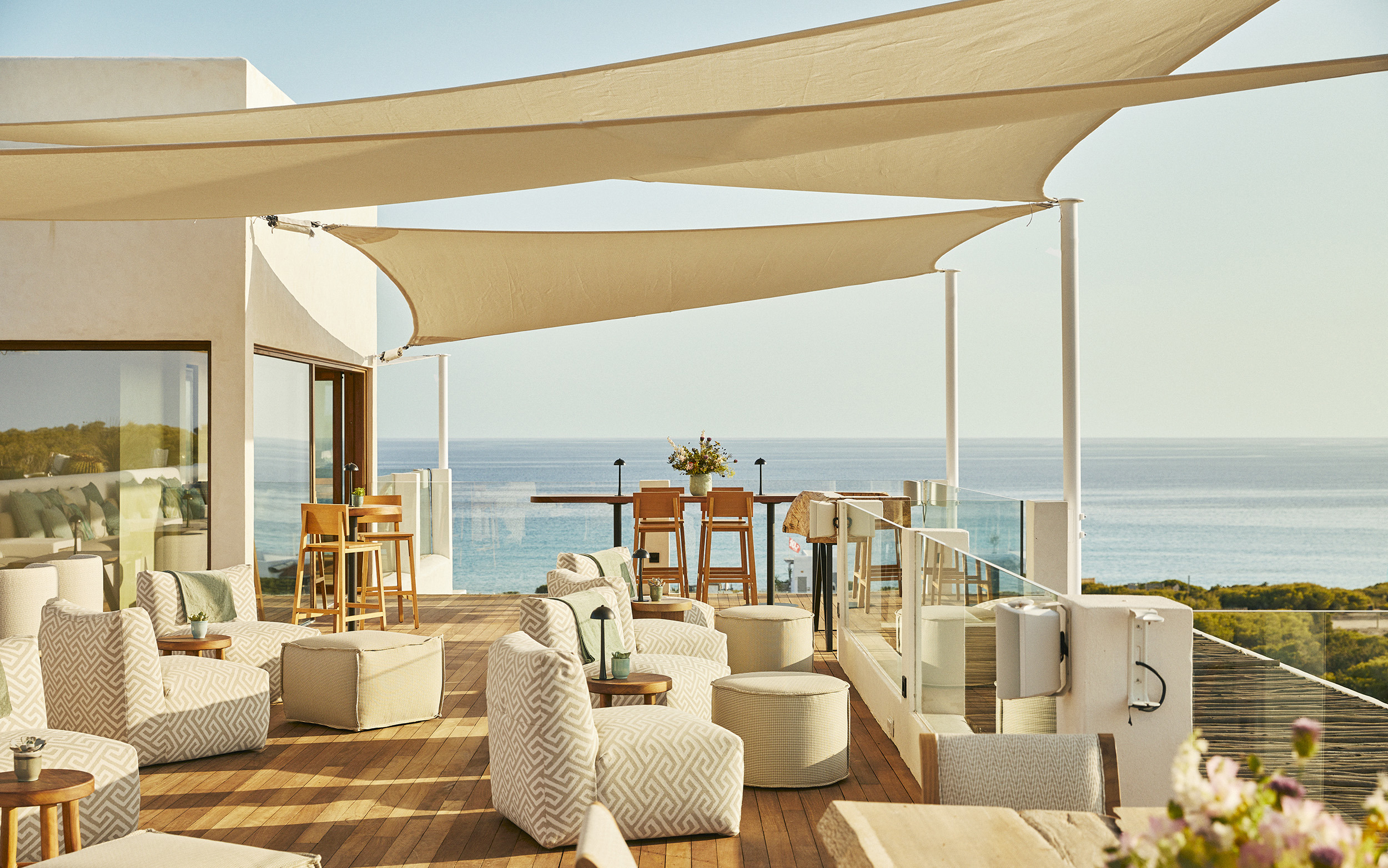 The modern bohemian rooftop of Teranka featuring comfy light coloured furniture beneath a fabric canopy with sweeping views of the ocean